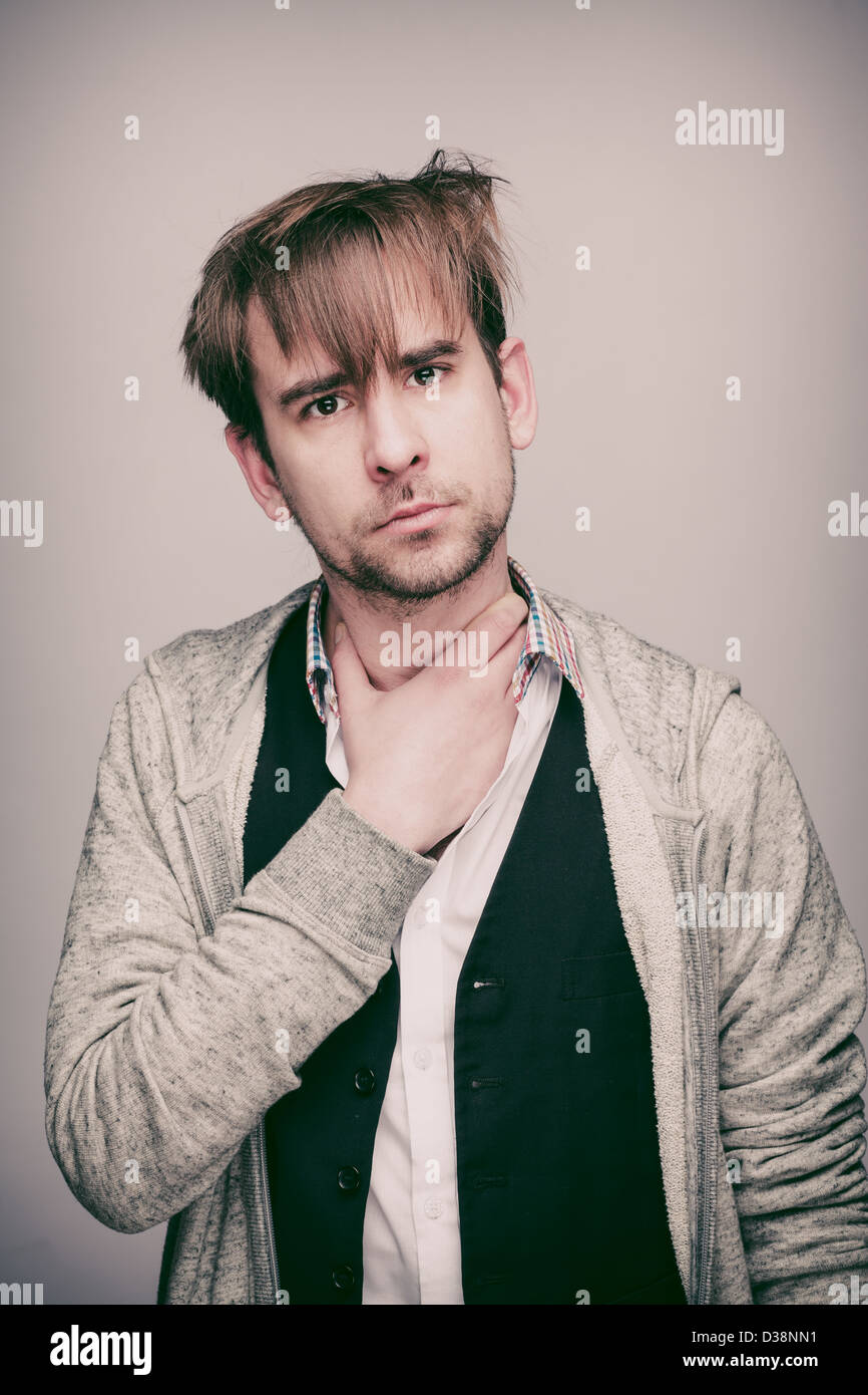 Uomo in venti in felpa con cappuccio grigia, camicia bianca e gilet nero,  con capelli selvaggi, avvolge la mano intorno alla sua gola e sembra  confusa Foto stock - Alamy