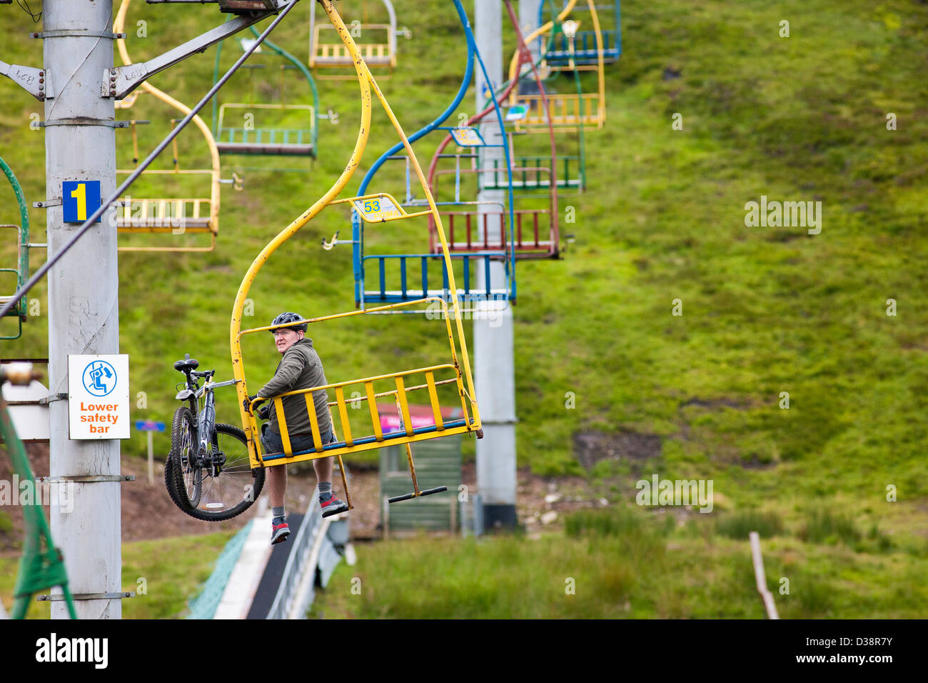 Un padre e figlio ride lo skilift fino alla montagna con le loro mountain bike in Scozia vicino a Invernss Foto Stock