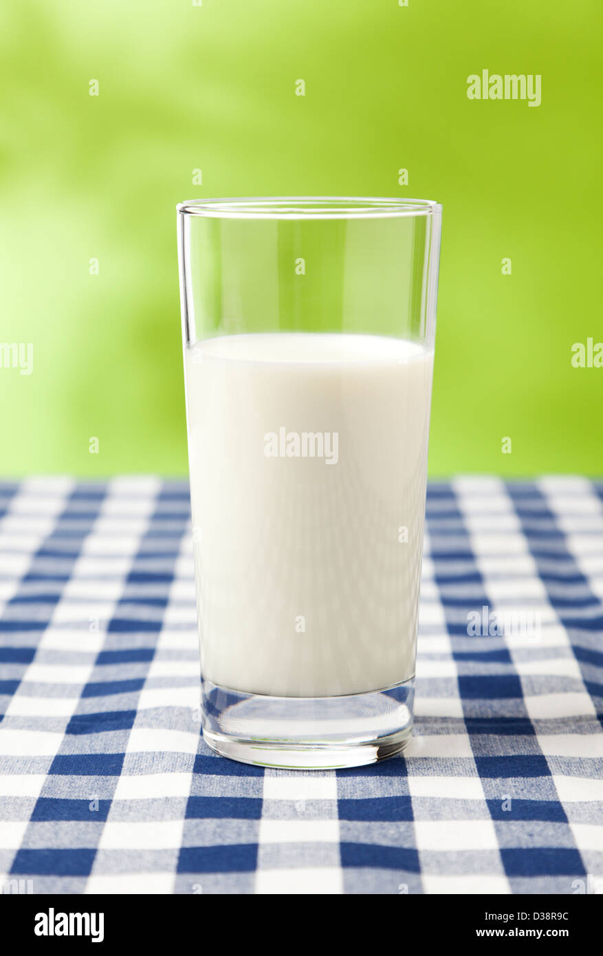 Bicchiere di latte sulla tavola a scacchi panno, sfondo verde Foto Stock