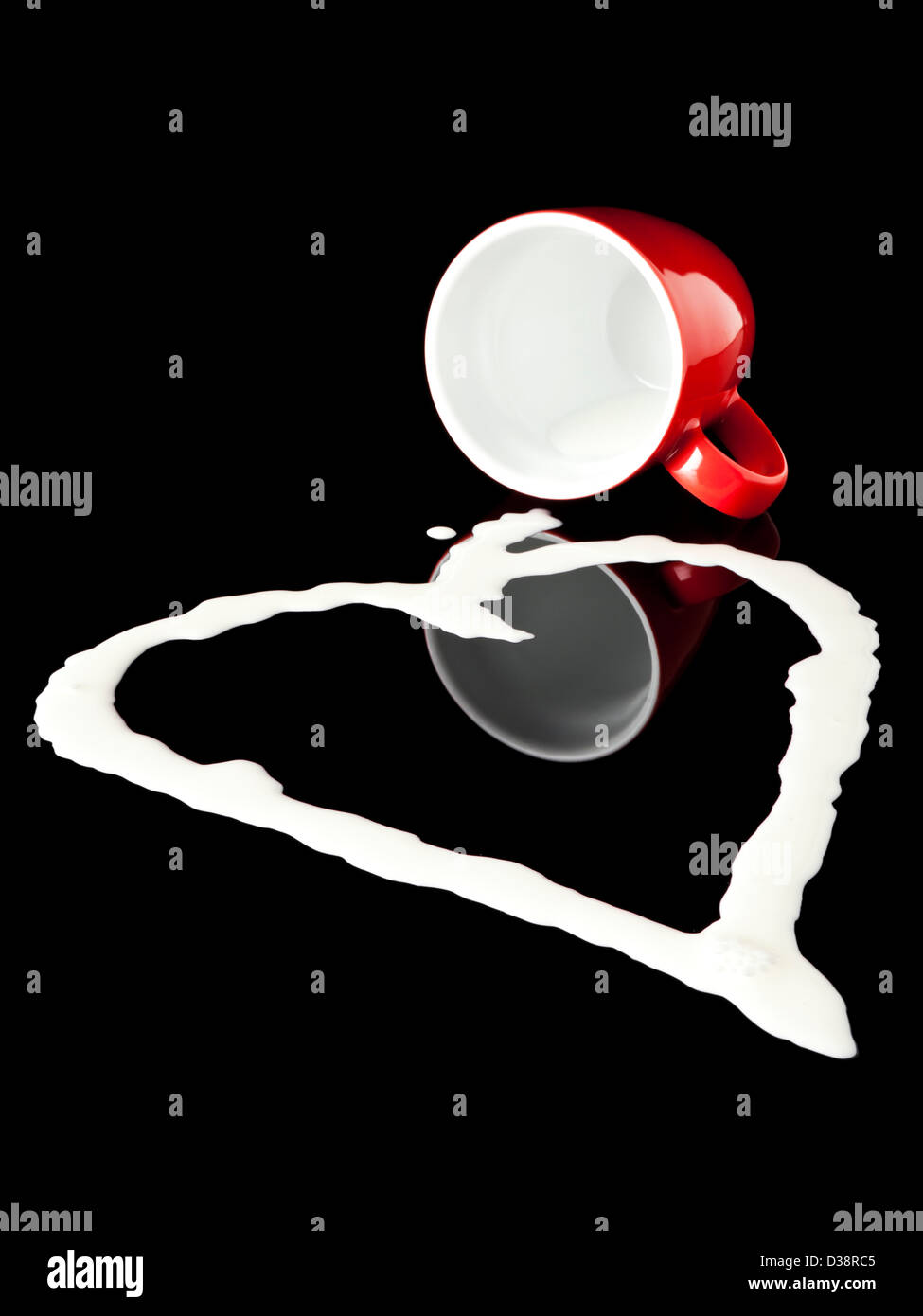 La fuoriuscita di latte da inclinato red mug, pozza conformata come un cuore, sfondo nero Foto Stock