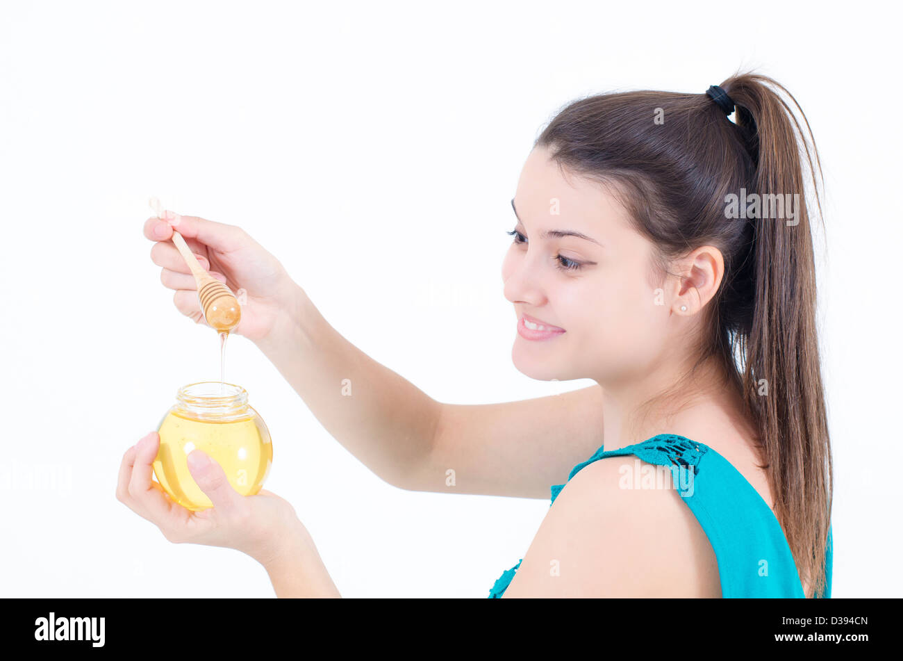 Una ragazza carina guardando il gocciolamento miele delle api Foto Stock