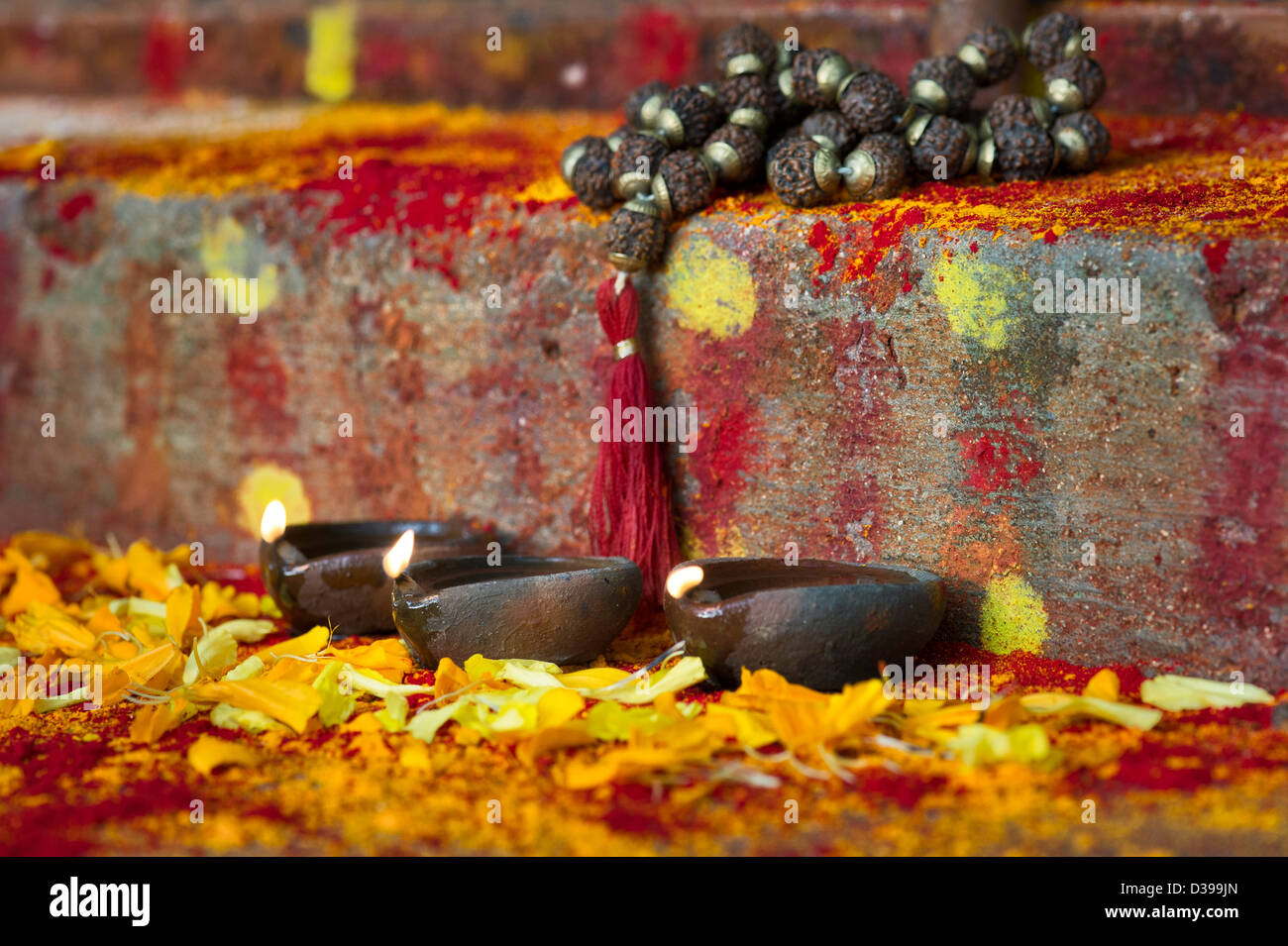 Lampade a olio e Rudraksha indiano / Japa Mala i grani di preghiera sui gradini di un rurale villaggio indiano il santuario / Tempio. India Foto Stock