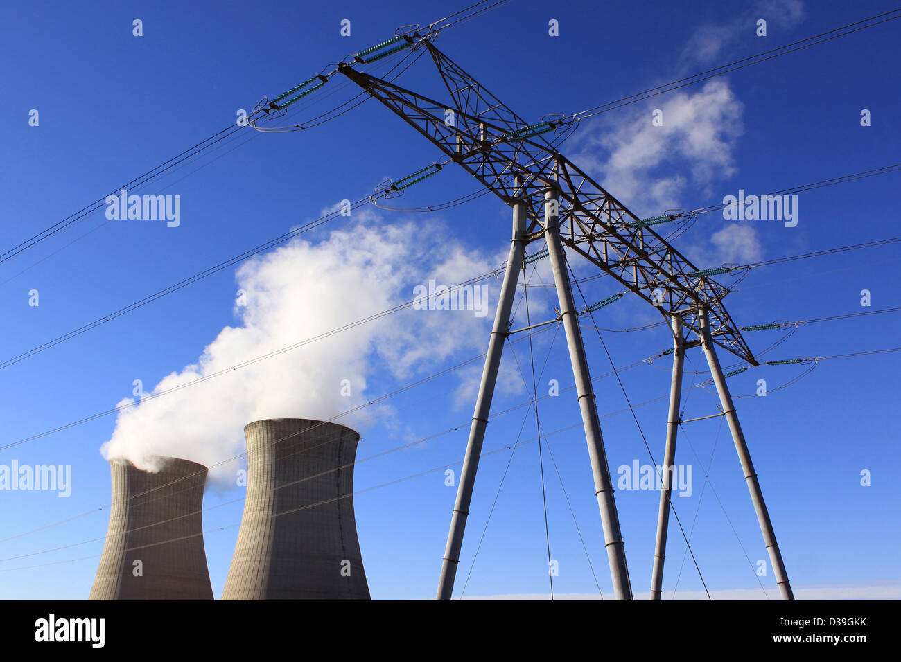 Ciminiere di una centrale nucleare con un pilone per le energie rinnovabili sul cielo blu sullo sfondo Foto Stock
