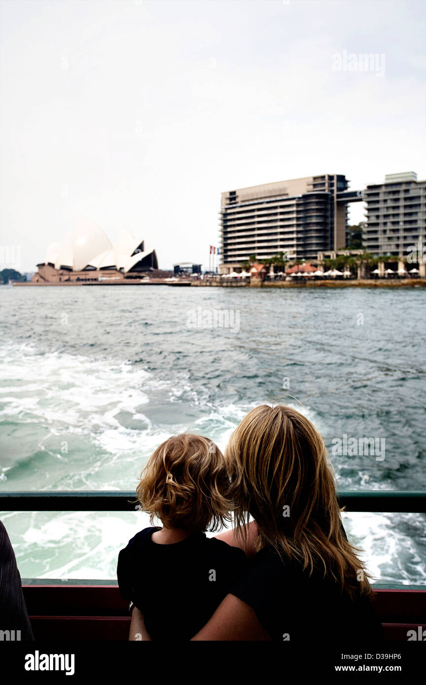 Una madre e figlio guardano fuori dal retro di un Ferry di Sydney alla Opera House di Sydney e il Sydney skyline. Foto Stock