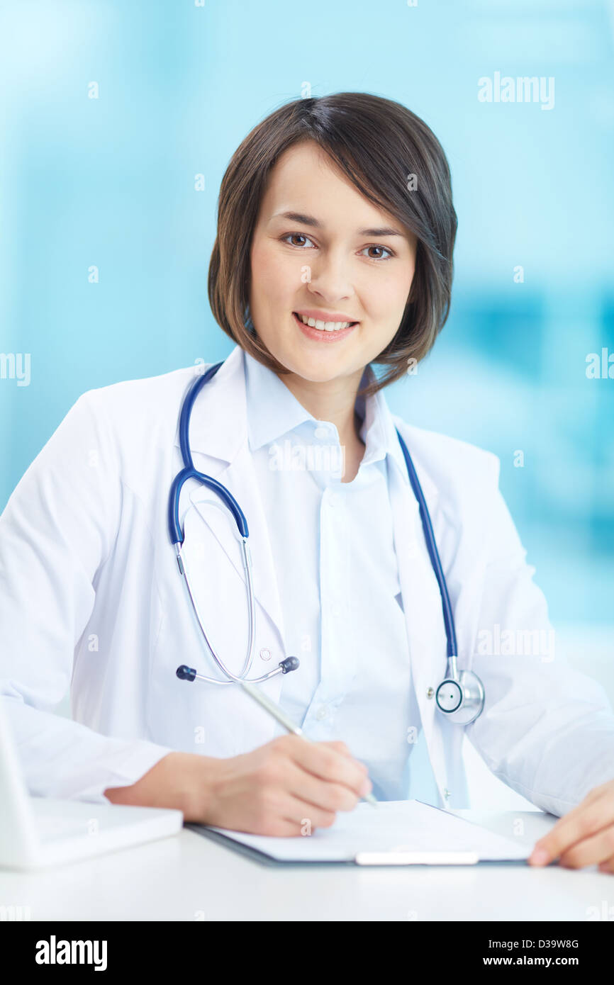 Ritratto verticale di un giovane medico donna al suo posto di lavoro Foto Stock