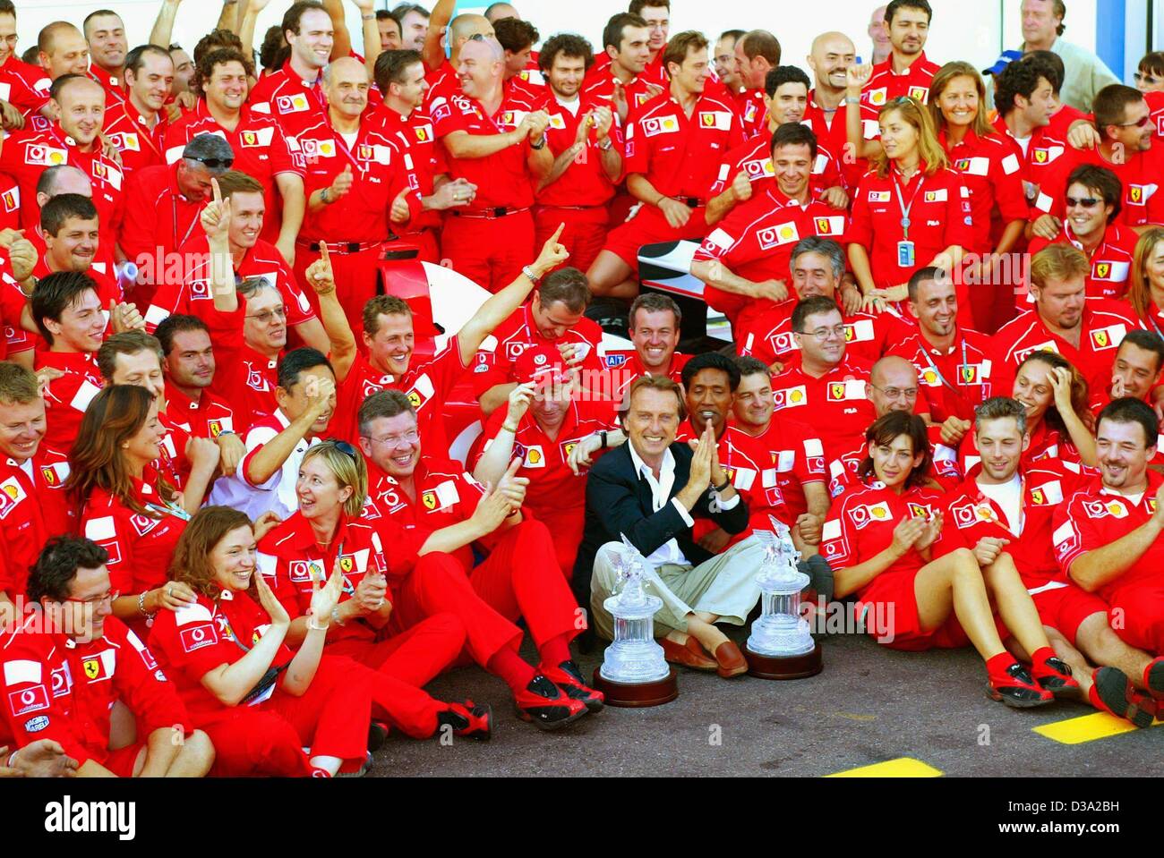(Dpa) - Il team Ferrari i membri e il presidente della Ferrari Luca di Montezemolo (con giacca nera) jubilate come essi posano per una foto di famiglia dopo Michael Schumacher (C) di sinistra ha vinto il francese FORMULA ONE Grand Prix sul circuito automobilistico di Magny-Cours in Francia, 21 luglio 2002. Grazie a questa vittoria di Schumacher ha vinto Foto Stock