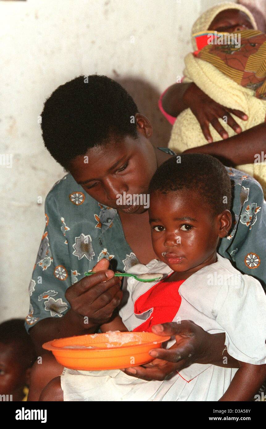 Un giovane helper è alimentazione di uno dei bambini orfani day care Center in Josamu, sud Malawi, 12 giugno 2001. Foto Stock