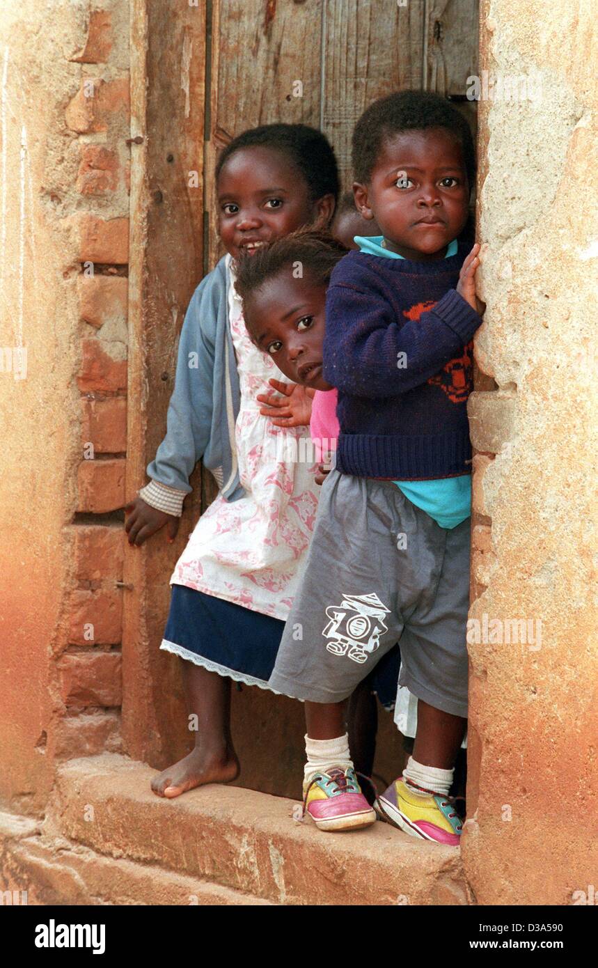 (Dpa) - Tre bambini curiosamente peer per i visitatori del Fondo delle Nazioni Unite per l'Infanzia (Unicef) dalla soglia dell'orfano day care Center in Josamu, sud Malawi, 12 giugno 2001. L' Unicef supporta il centro dove 60 bambini sono presi cura del. La maggior parte di loro hanno perso entrambi i genitori per l AIDS Foto Stock