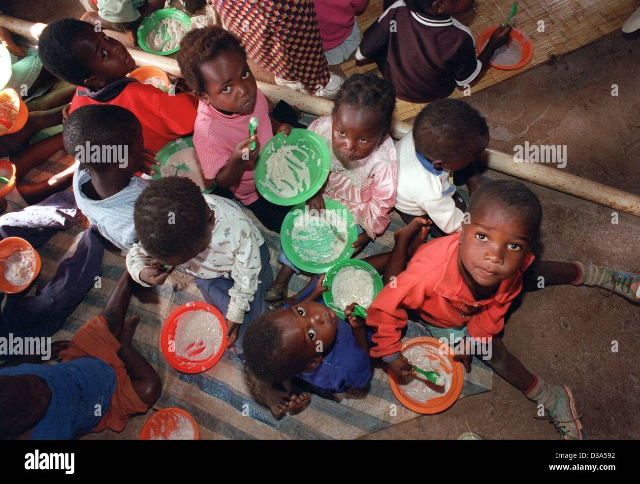 (Dpa) - i bambini prendono il loro pranzo seduti sul pavimento in orfana del centro diurno in Josamu, sud Malawi, 12 giugno 2001. Il Fondo delle Nazioni Unite per l'Infanzia (Unicef) supporta il centro dove 60 bambini sono presi cura del. La maggior parte di loro hanno perso entrambi i genitori per il virus dell AIDS e molti di loro portano Foto Stock