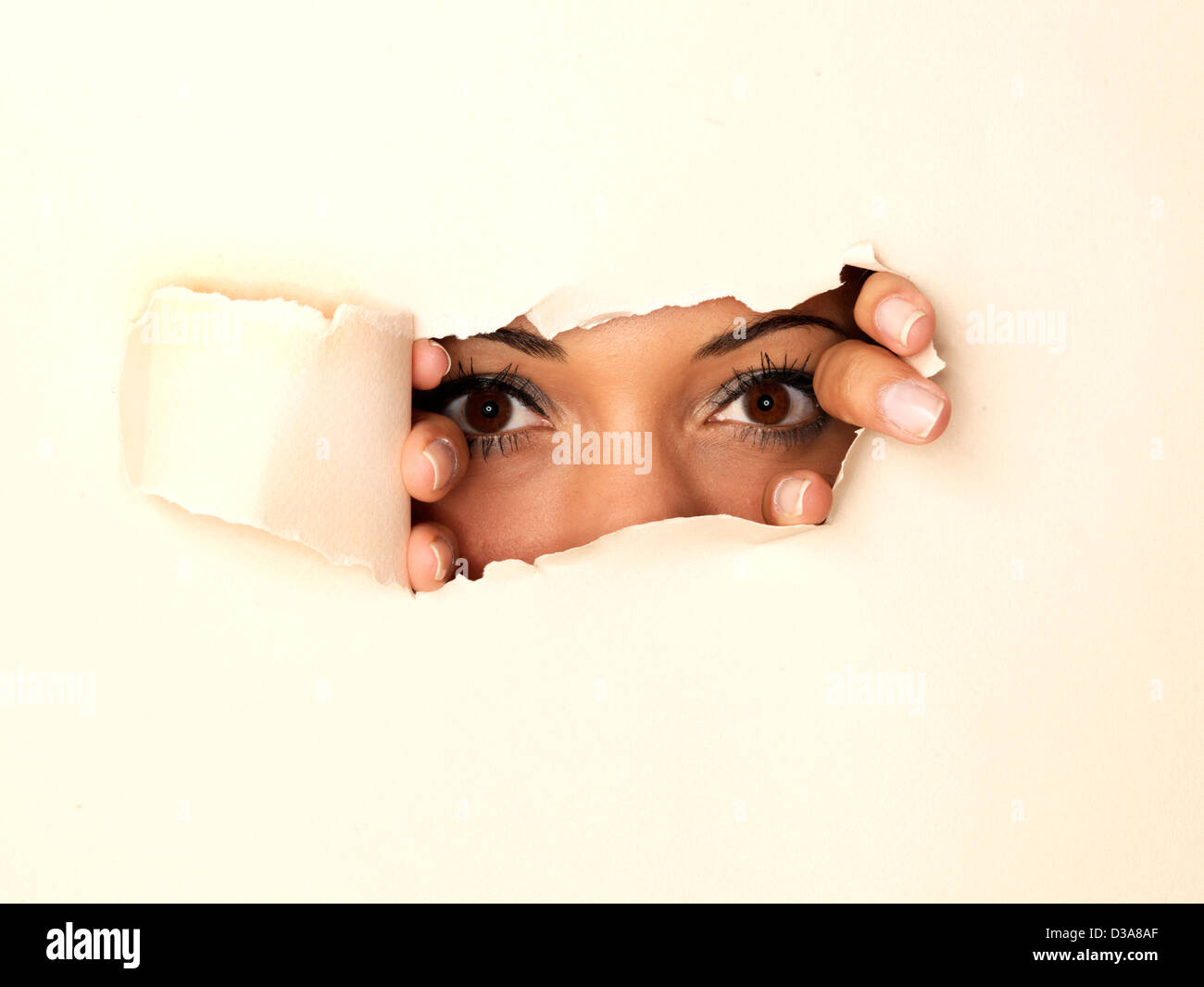 Donna spiata attraverso il foro nella parete Foto Stock
