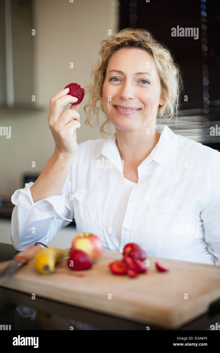 Donna mangiare la frutta in cucina Foto Stock