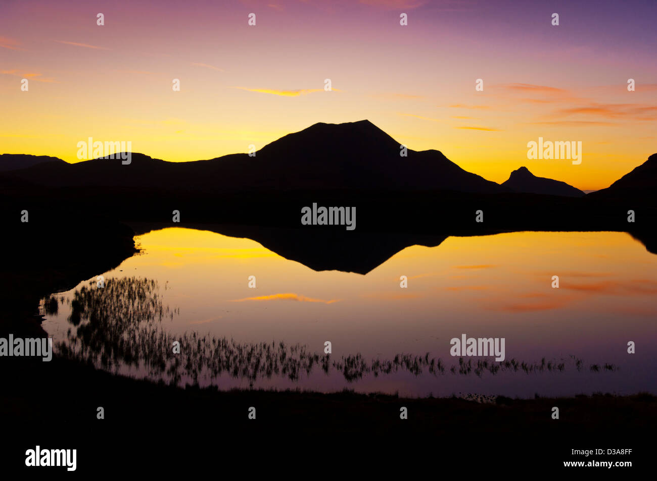Silhouette di un Lochan perfetto specchio un Ais al tramonto nella Riserva naturale di Inverpolly Sutherland Scotland UK GB Europe Foto Stock