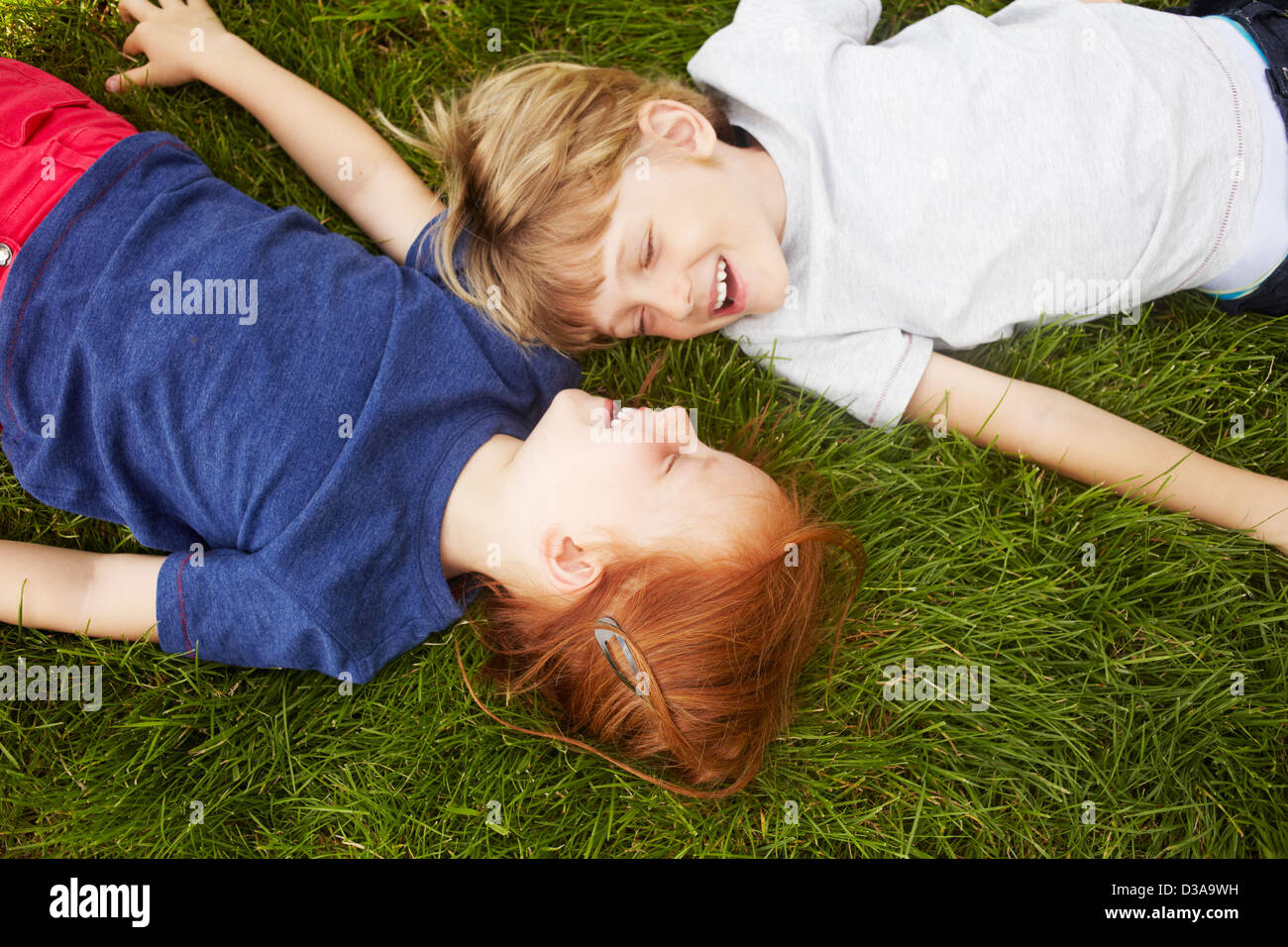 Bambini sorridenti che stabilisce in erba insieme Foto Stock