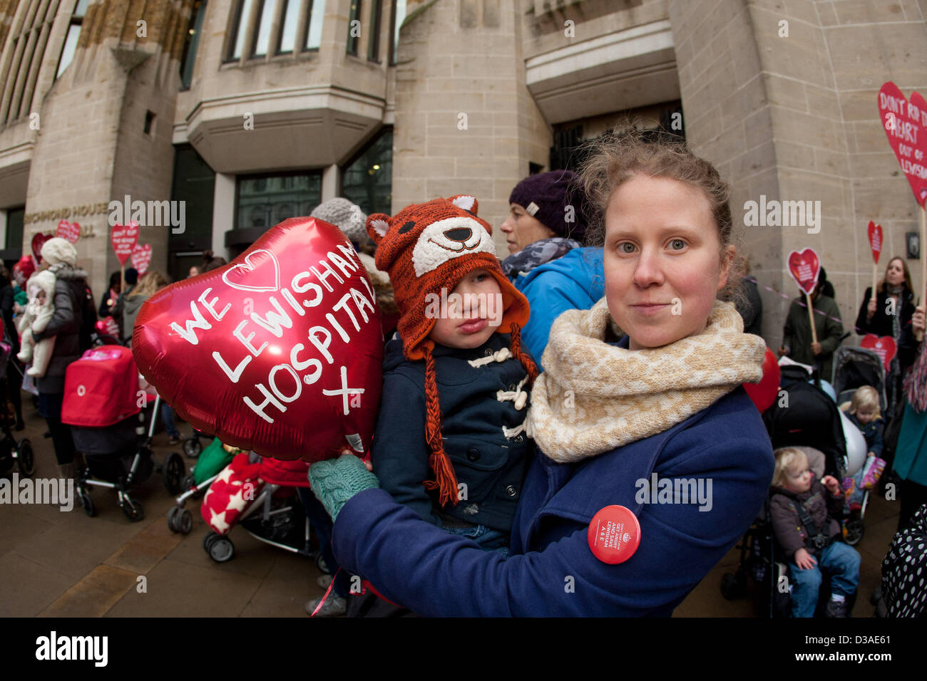 Londra, Regno Unito. 14 febbraio 2013. Donna che mantiene il bambino e a forma di cuore ad palloncino con la lettura del messaggio che amiamo Lewisham ospedale al di fuori del Reparto di Salute, offrendo un Valentine-tema messaggio: "Hanno un cuore Hunt'. È in risposta alla Segretaria di salute Jeremy cacce al piano approvato per il downgrade di Lewisham ospedale A&E e servizi di maternità. Londra, UK, 14 febbraio 2013. Credito: martyn wheatley / Alamy Live News Foto Stock