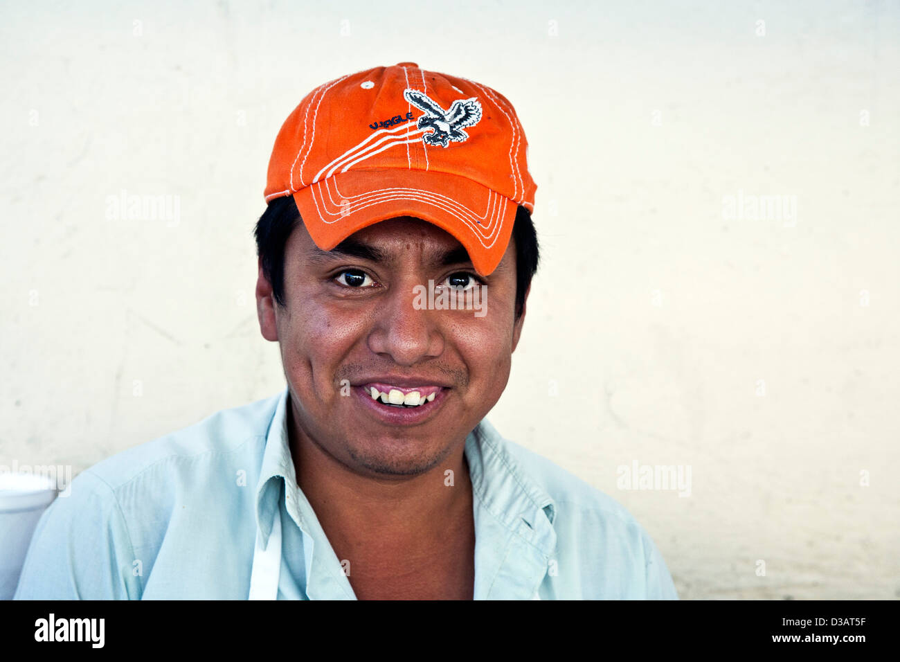 Sorridenti giovane messicano uomo venditore ambulante che indossa l'arancione cappello da baseball godendo di lavorare su una strada in Oaxaca de Juarez Mexico Foto Stock