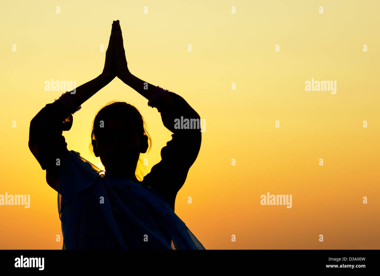 Indian ragazza adolescente pregando al tramonto indossa un velo di stelle. Silhouette. India Foto Stock
