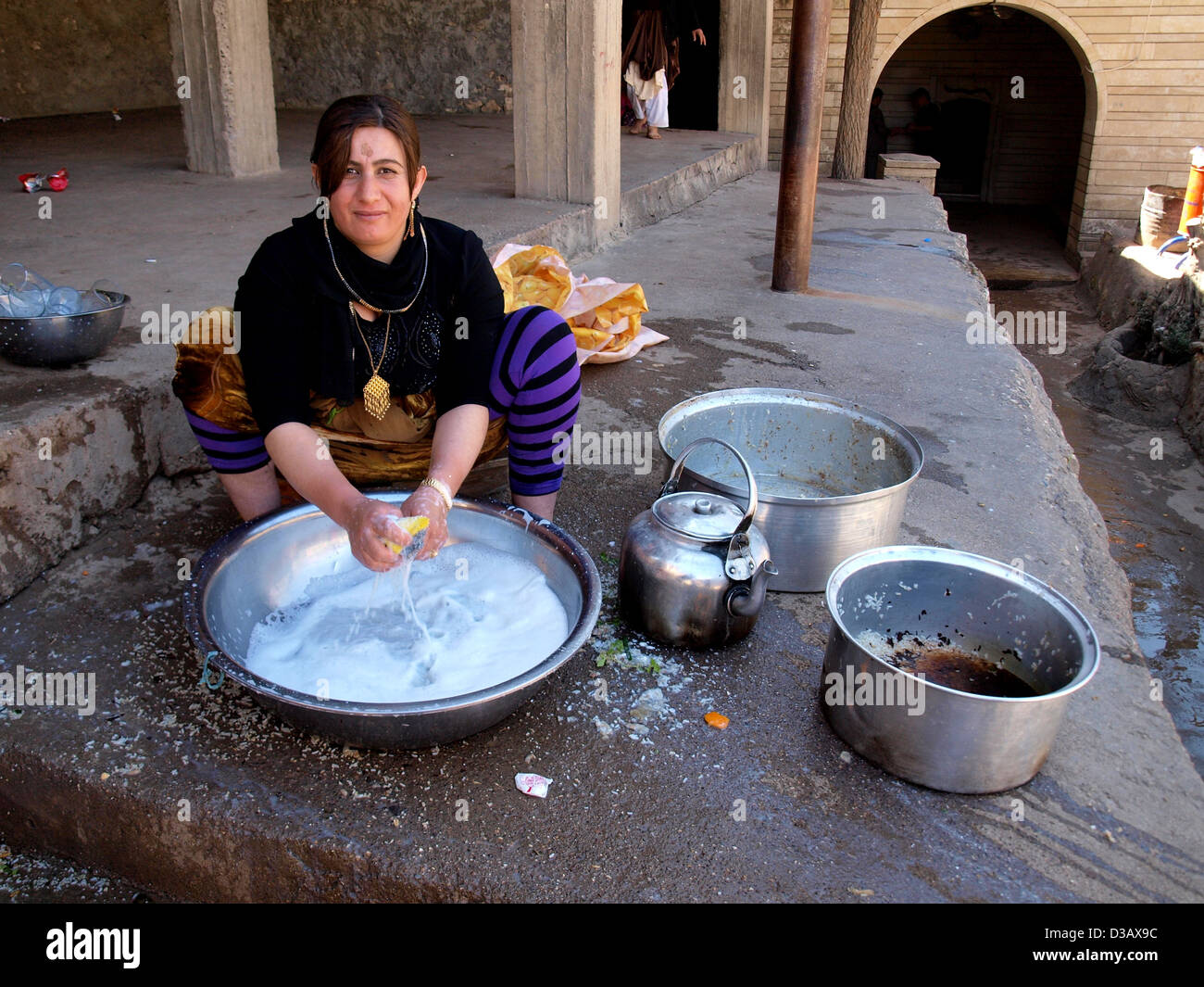 Curdi yazidi donna il lavaggio a mano di biancheria in Lalish, nell Iraq del Nord. Foto Stock