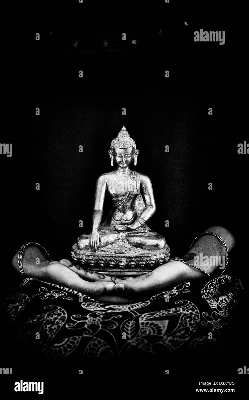 Statua del Buddha seduto sulle mani di una ragazza indiana. India. Monocromatico Foto Stock