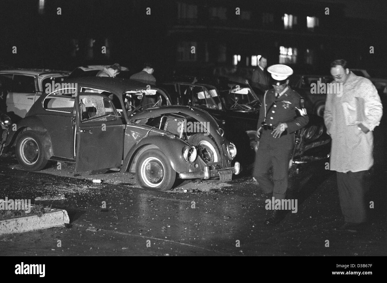 (Dpa file) - In Germania un funzionario di polizia e un ufficiale della US polizia militare raffigurato nella parte anteriore del scatafascio VW Beetle in cui una delle bombe esplose su di noi quartier generale militare a Heidelberg, Germania Ovest, 24 maggio 1972. Tre soldati americani sono stati uccisi e cinque feriti quando due bombe Foto Stock