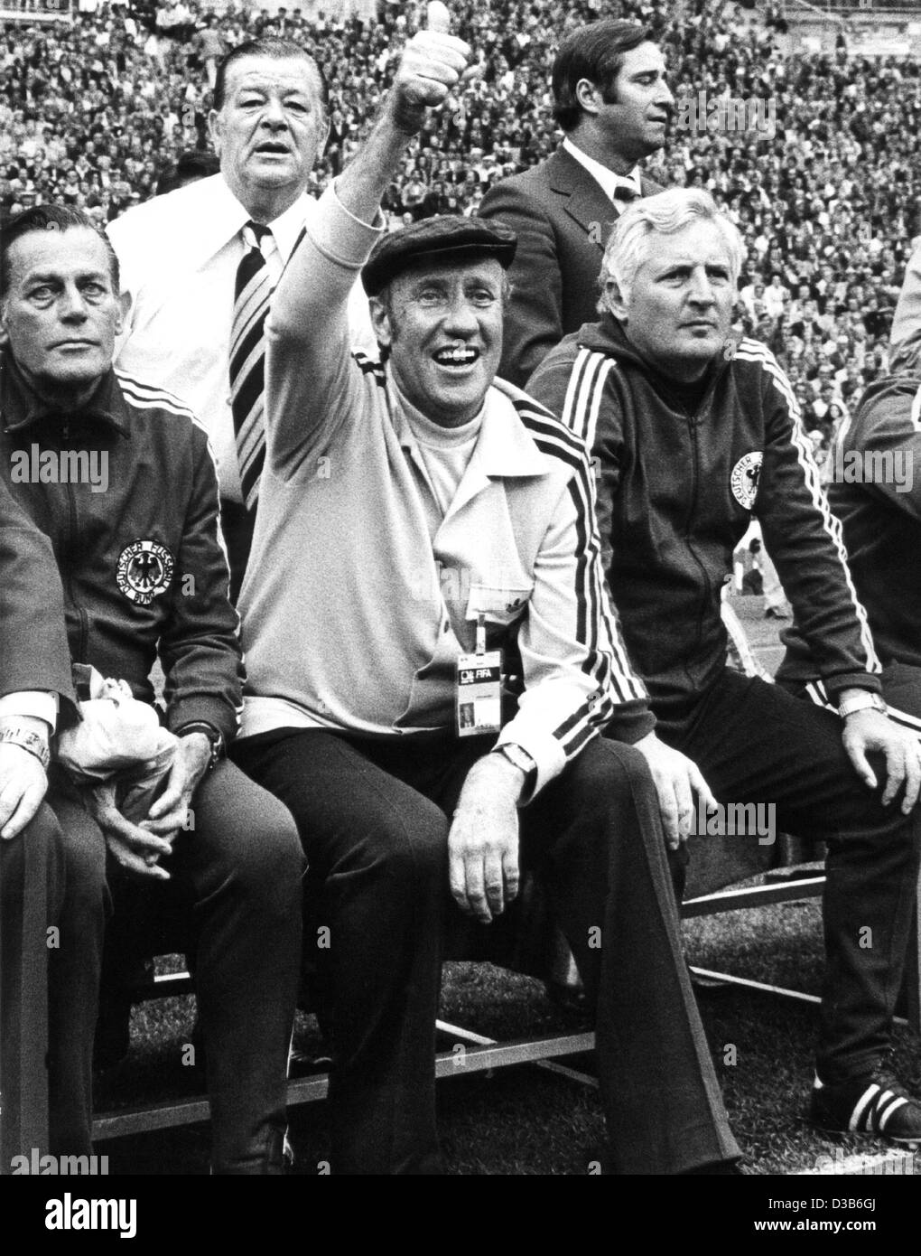 (Dpa file) - calcio tedesco coach Helmut Schoen segnali i suoi giocatori "un minuto in più!" durante la fase finale della Coppa del Mondo a Monaco di Baviera, 7 luglio 1974. Accanto a lui siedono assistant coach Hans Widmayer (L) e co-trainer Jupp Derwall (R). La Germania ha sconfitto i Paesi Bassi 2:1. Schoen allenata il tedesco n Foto Stock