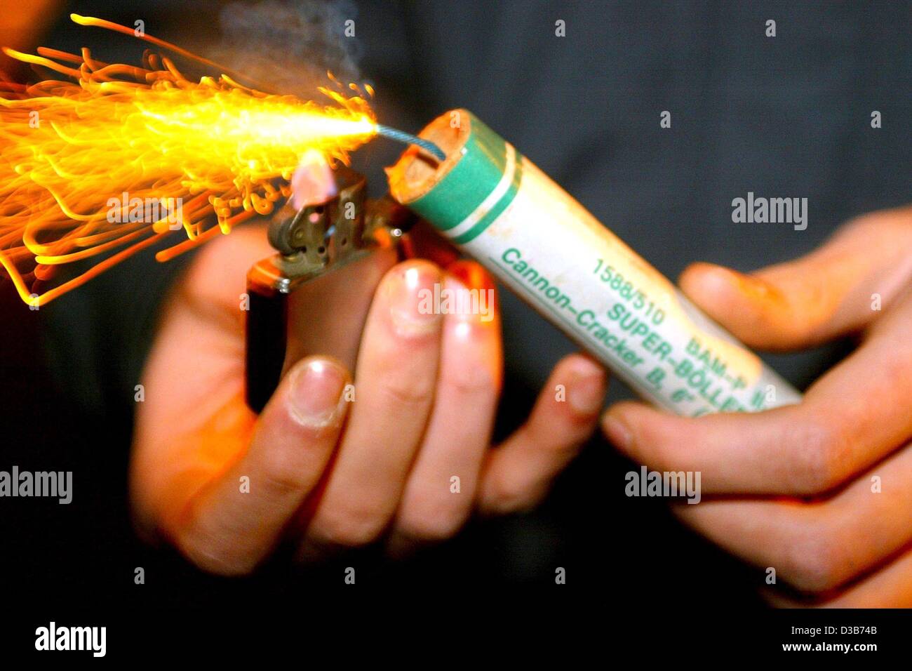 Dpa) - Un giovane uomo accende la miccia di un razzo pirotecnico che è  bloccata in una bottiglia vuota, a Magdeburgo (Germania), 28 dicembre 2002.  È ufficialmente consentito di sparare petardi e