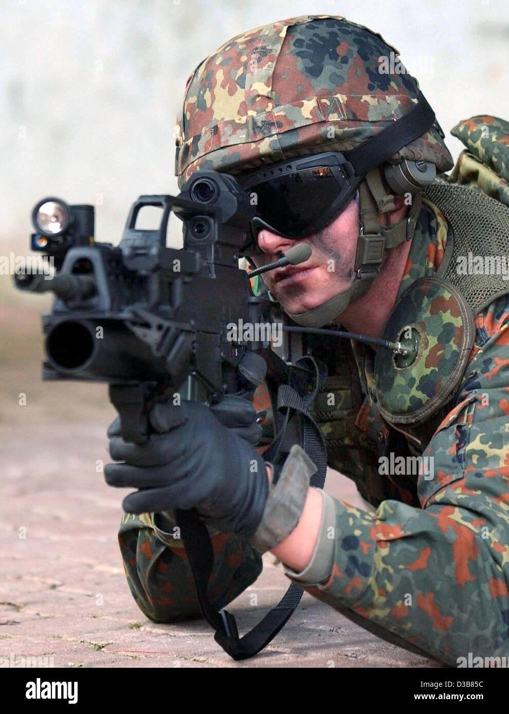 Un soldato equipaggiato con l'arma hi-tech prototipi è finalizzata a un obiettivo attraverso una vista laser montato sulla sua pistola a Hammelburg, Germania, 9 dicembre 2002. Il 'fante del futuro' porta antenne di comunicazione e un sistema di navigazione satellitare. Sebbene la sua paternità è pesantemente blindate si tratta di peso Foto Stock