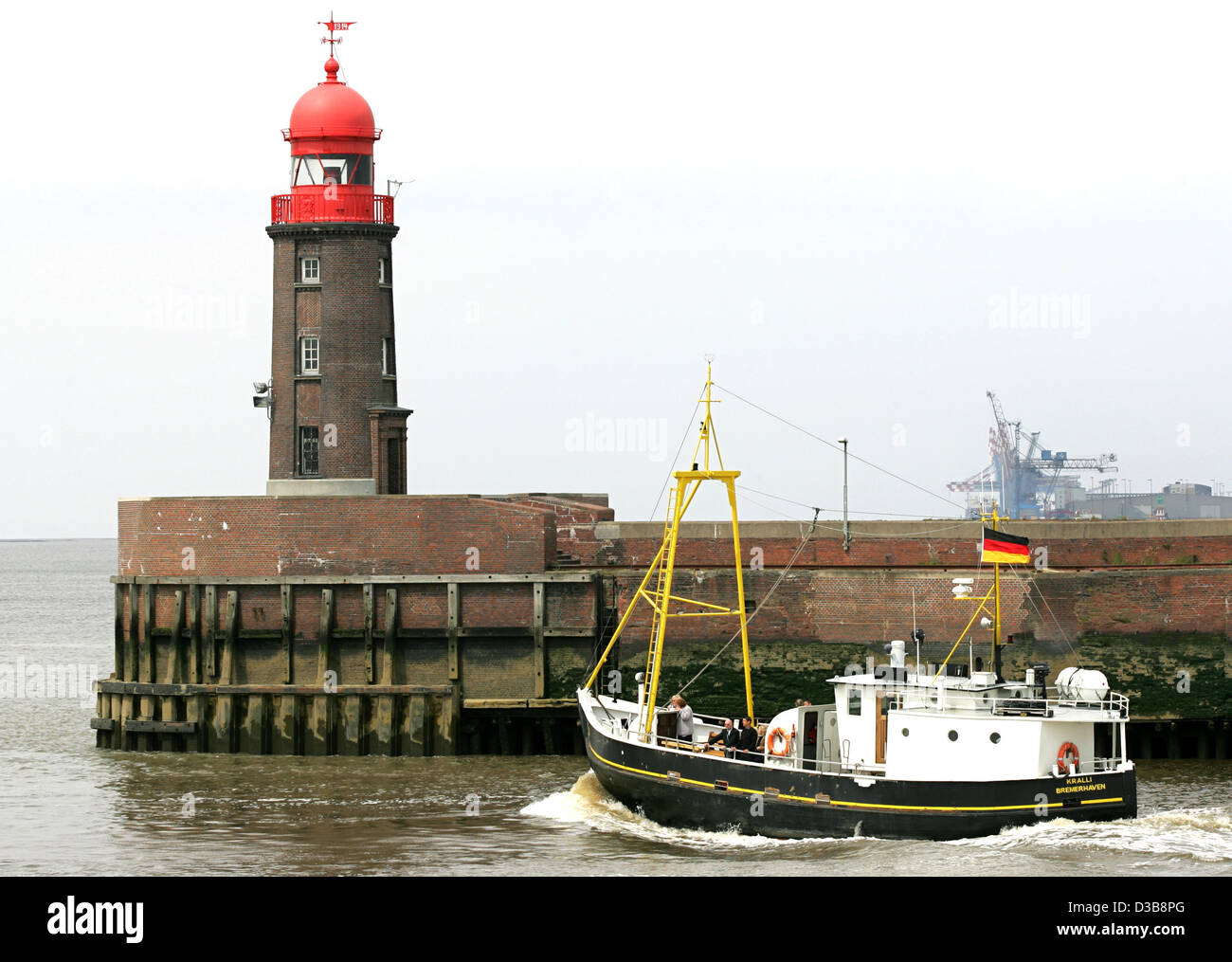 (Dpa) - una barca da pesca passa il faro di punta-fine del molo nord all'ingresso del Geestevorhafen porto di Bremerhaven, Germania, 16 giugno 2005. Foto Stock