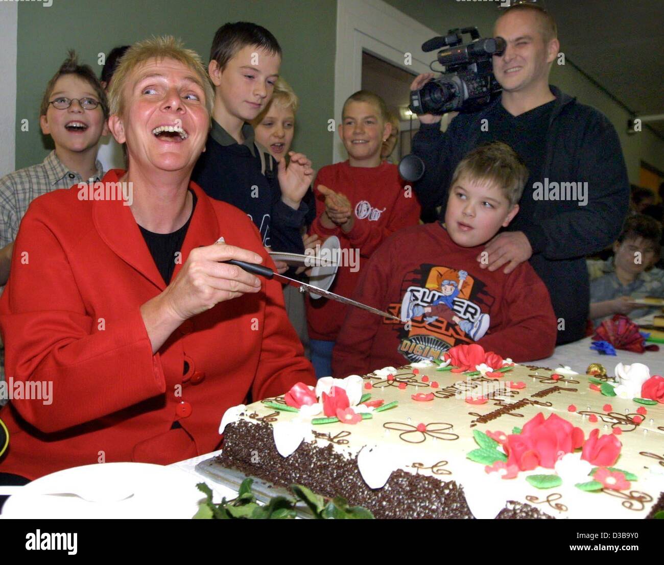 (Dpa) - Marianne Buggenhagen, Germania più famosi atleti disabili, ride come lei inizia a tagliare una fetta di torta presso la scuola speciale per bambini disabili che sarà chiamato dopo il suo, in Darlingerode, Germania, 25 ottobre 2002. Il sette volte vincitore Paralimpiadi è stato eletto anche Atleta dell'anno 1994. Foto Stock