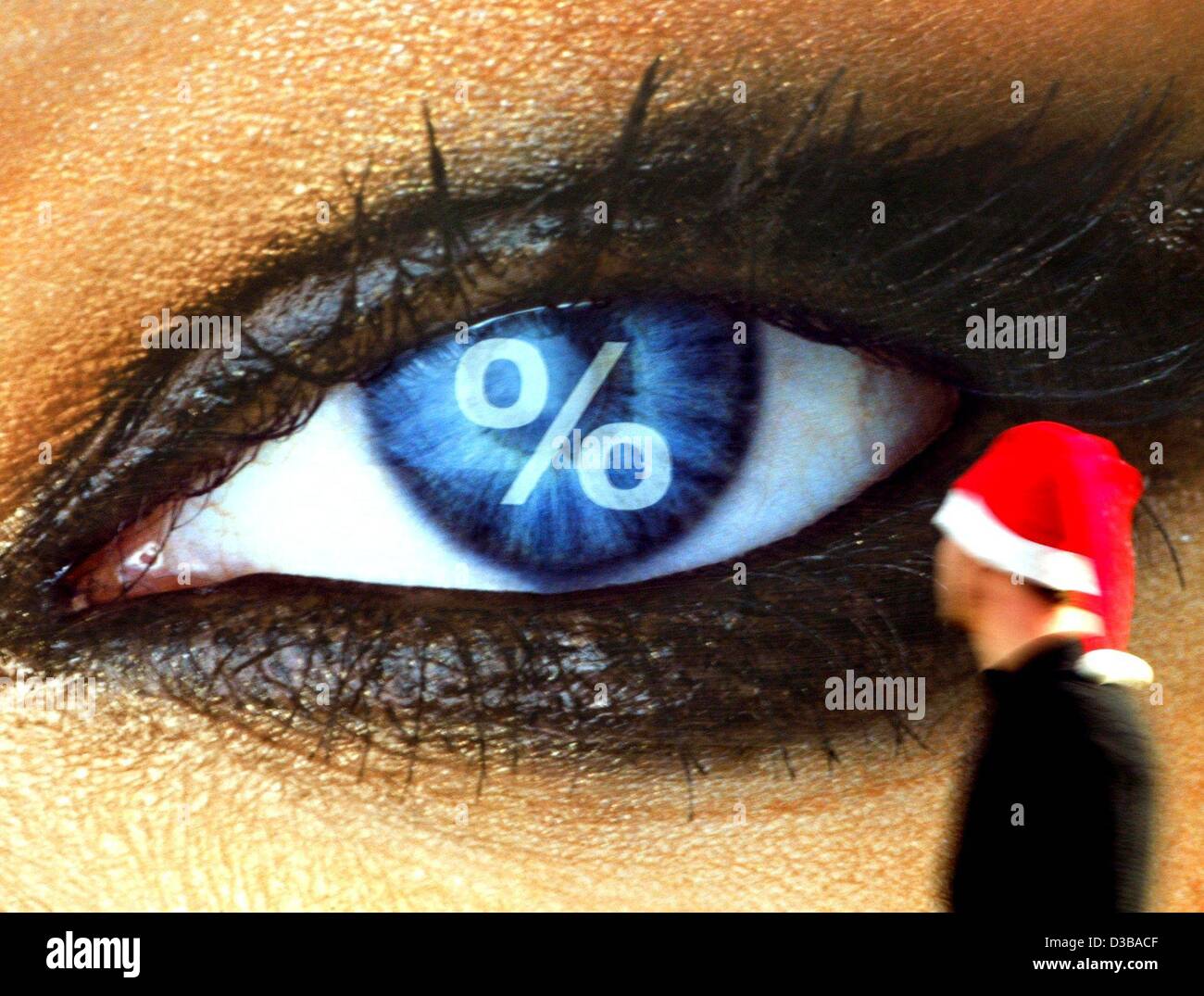 (Dpa) - Un poster che mostra un grande occhio con un per cento segno cattura l'occhio di un passante che indossa un Berretto di Babbo Natale a Duesseldorf in Germania, 25 novembre 2002. Il poster annuncia le vendite in un centro di outlet, che vende articoli di marca più conveniente che i dettaglianti. Foto Stock
