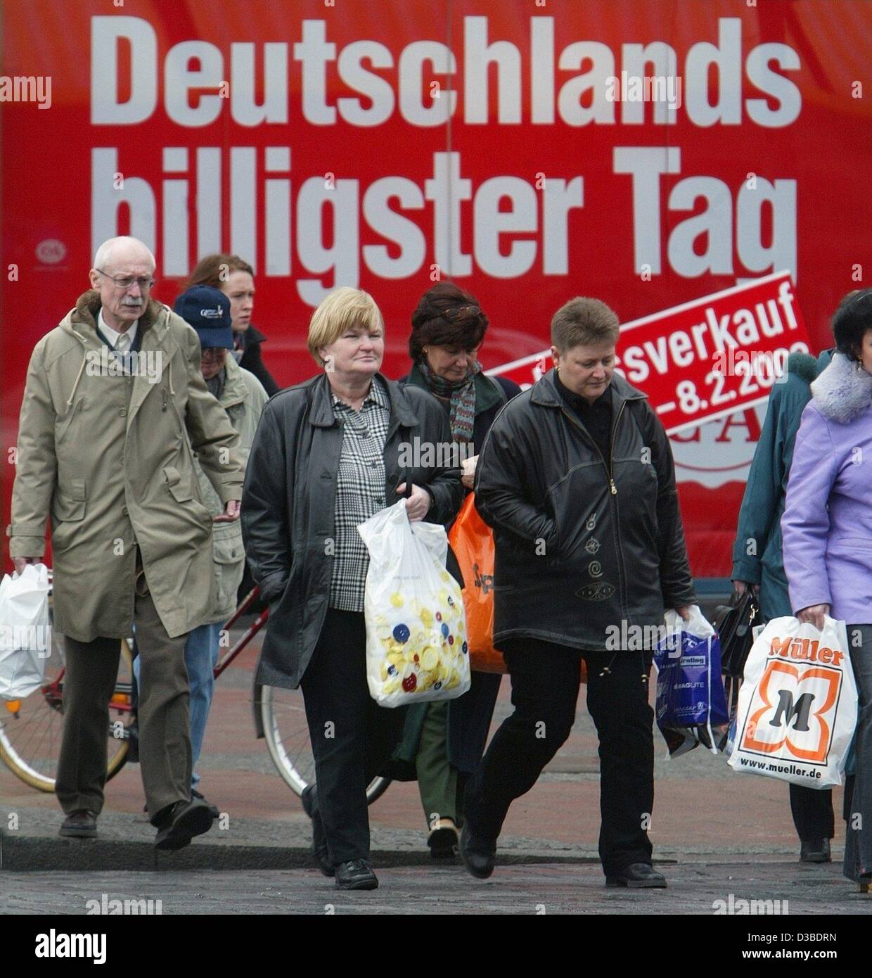 (Dpa) - gli acquirenti che trasportano i sacchetti di plastica a piedi passato alla vetrina di un negozio che annuncia "Germania il giorno più conveniente' a Magdeburgo, Germania, 27 gennaio 2003. In inverno le vendite in Germania eseguire attraverso il 8 febbraio 2003. Foto Stock