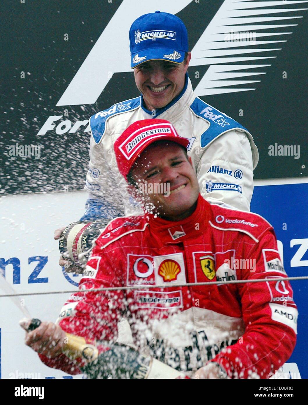 (Dpa) - Tedesco pilota di Formula Uno e vincitore della gara di Ralf Schumacher (BMW-Williams, indietro) versa la sua bottiglia di champagne oltre il terzo posto di Rubens Barrichello dal Brasile dopo il Gran Premio Europeo al Nuerburgring race track, Germania, 29 giugno 2003. Con 43 punti in classifica generale per la Foto Stock