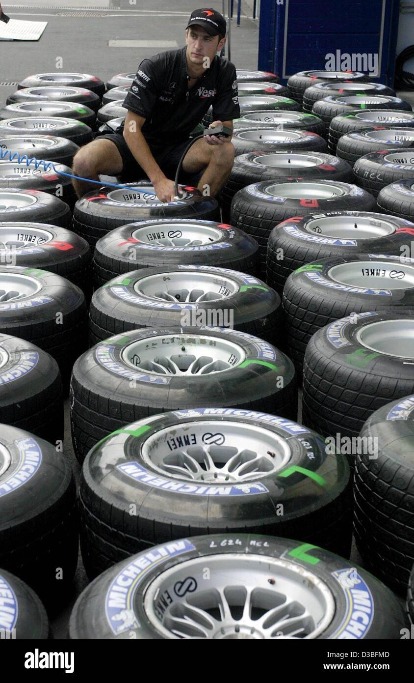 (Dpa) - Un meccanico di McLaren-Mercedes ispeziona la pressione di aria di formula one racing pneumatici realizzati da Michelin per il team del Nuerburgring racetrack, Germania, 26 giugno 2003. La FORMULA ONE Grand Prix Europeo avrà inizio il 29 giugno 2003. Foto Stock