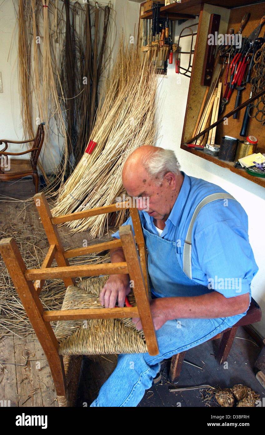 (Dpa) - Basket maker Rudolf Ammann si siede su una panchina e lavora su sedute di una sedia nella sua officina a Oberstdorf in Germania, 20 maggio 2003. Egli è uno degli ultimi artigiani in questo commercio. Prodotti industriali cestelli sono ora disponibili in ogni negozio ma Ammann può orgoglio di sé con fatti a mano Foto Stock