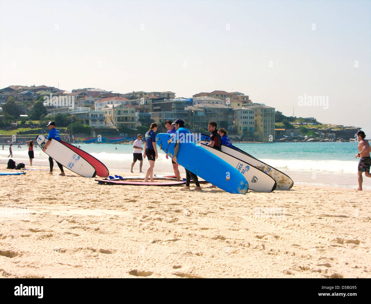 Persone che trasportano tavole da surf sulla spiaggia di bondi a Sydney, nuovo Galles del Sud, Australia e frequentano la scuola di surf Foto Stock