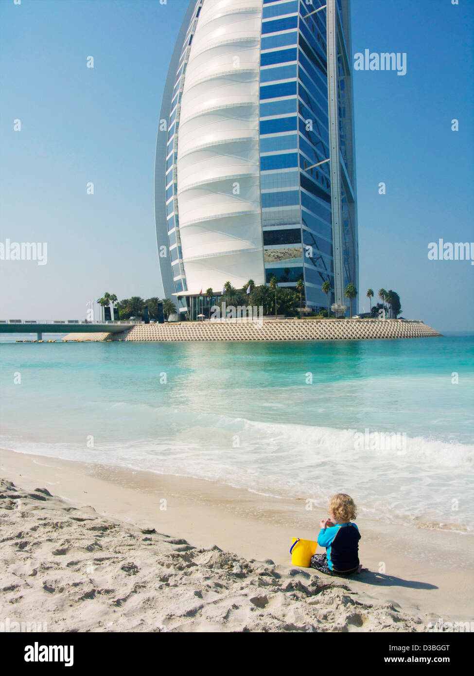 Le sette stelle di 'Sail nel deserto' Burj al Arab Hotel di lusso in background di un piccolo ragazzo giocando sulla spiaggia in Dubai EMIRATI ARABI UNITI Foto Stock