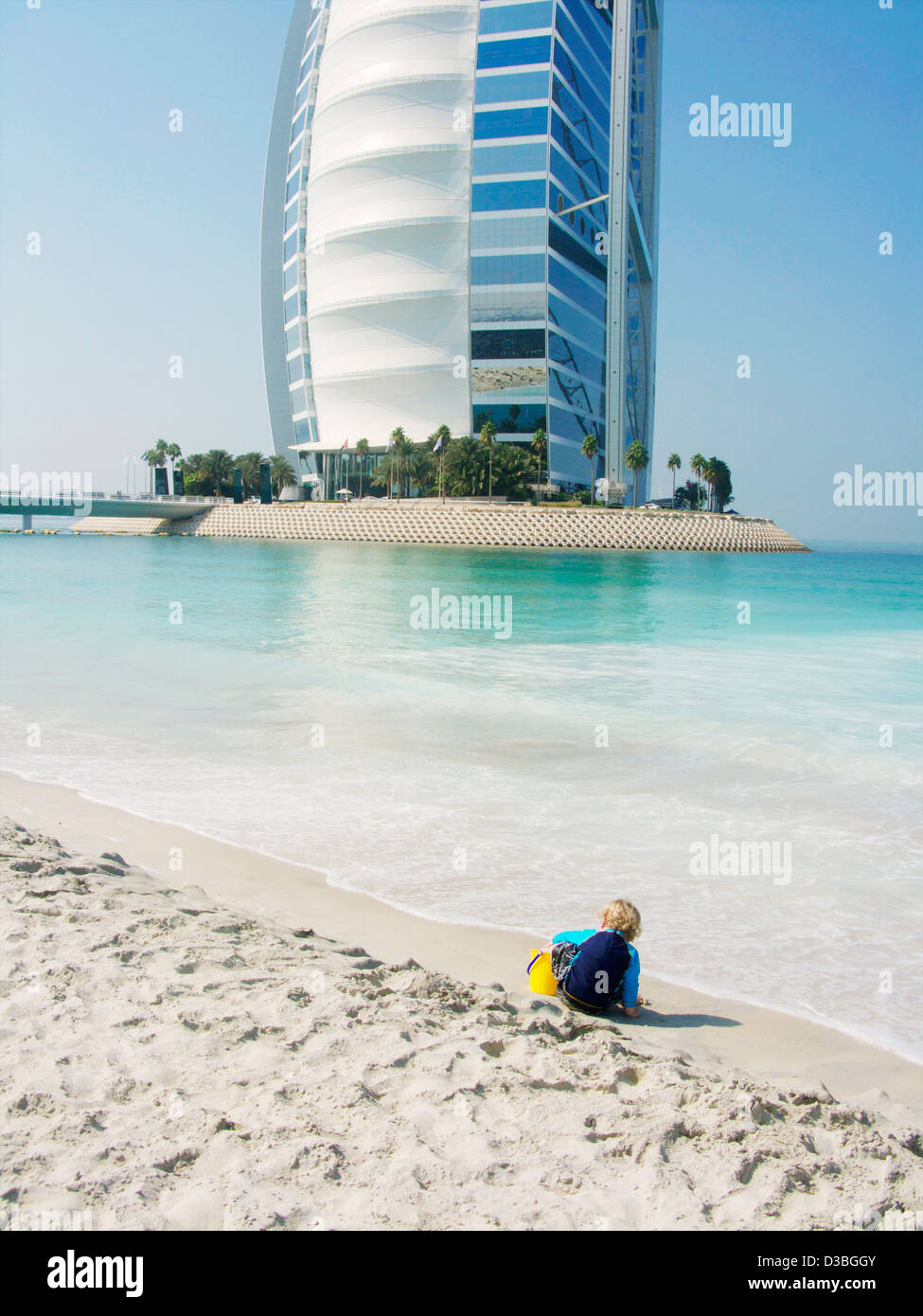 Le sette stelle di 'Sail nel deserto' Burj al Arab Hotel di lusso in background di un piccolo ragazzo giocando sulla spiaggia in Dubai EMIRATI ARABI UNITI Foto Stock