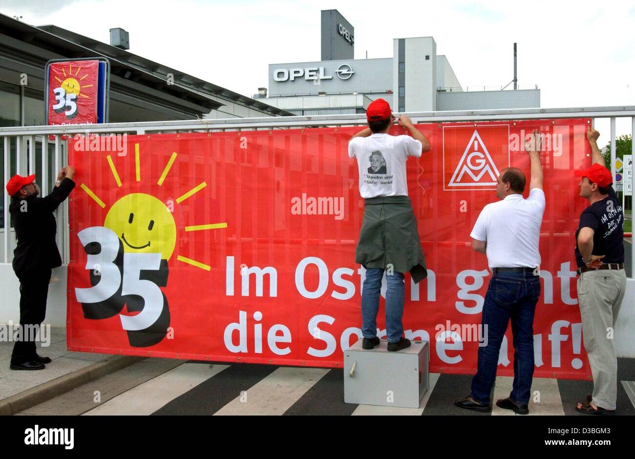 (Dpa) - Membri del tedesco di metallo lavoratori sindacato IG Metall sono appesi un enorme striscione al cancello della Opel fabbrica di automobili a Eisenach, 12 maggio 2003. Il banner dice "il sole è in aumento in oriente' ('im Osten geht die Sonne auf') e mostra il logo di un sole sorridente e lucenti oltre la figura 35. Foto Stock