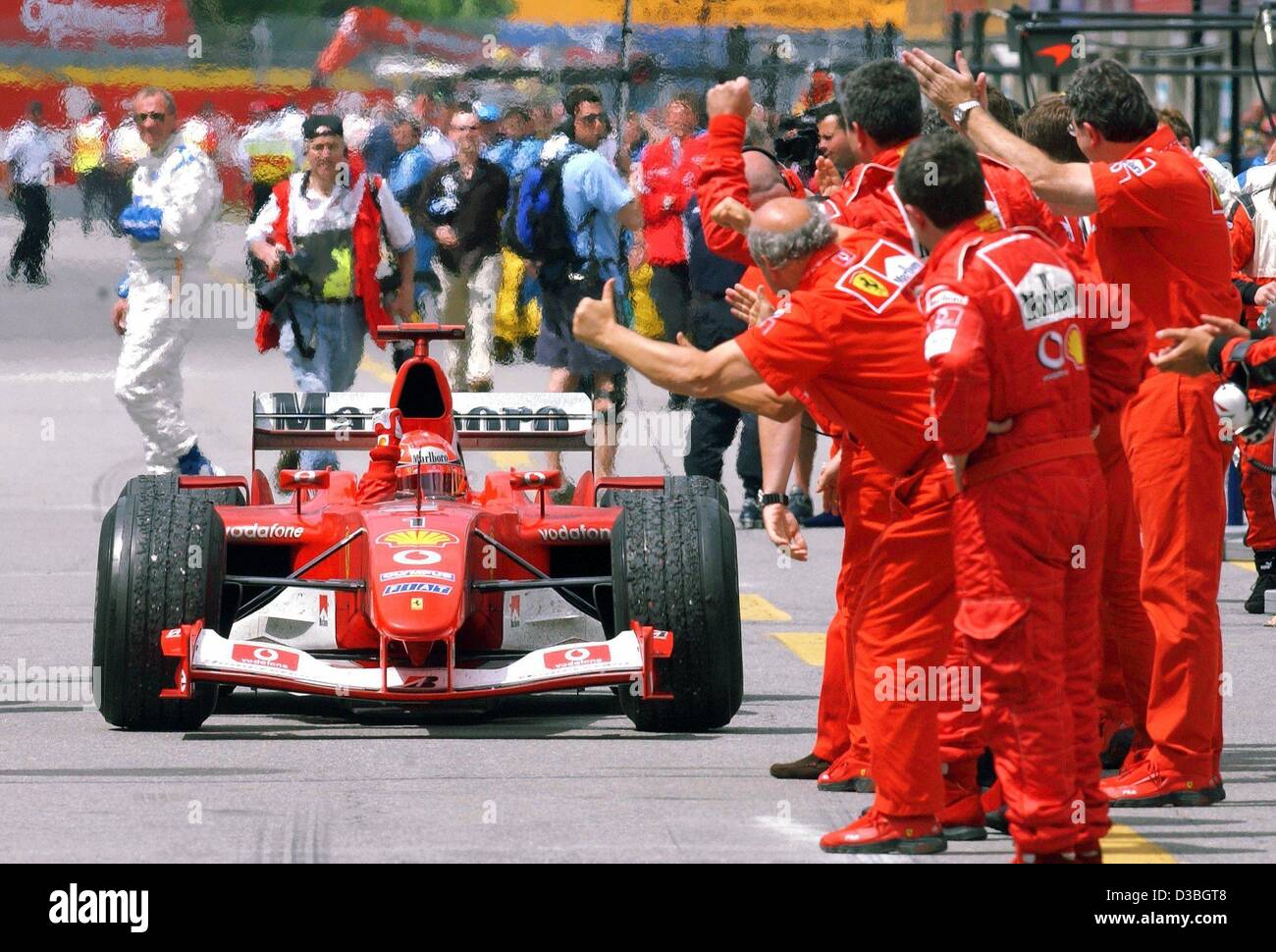 (Dpa) - i meccanici della Ferrari allegria mentre tedesco di Formula Uno del campione del mondo in carica Michael Schumacher (Ferrari) rigidi li passato nella sua formula one racing car sul Circuito Gilles Villeneuve formula one racing via durante il Gran Premio del Canada a Montreal, Canada, 15 giugno 2003. Michael Schumacher Foto Stock