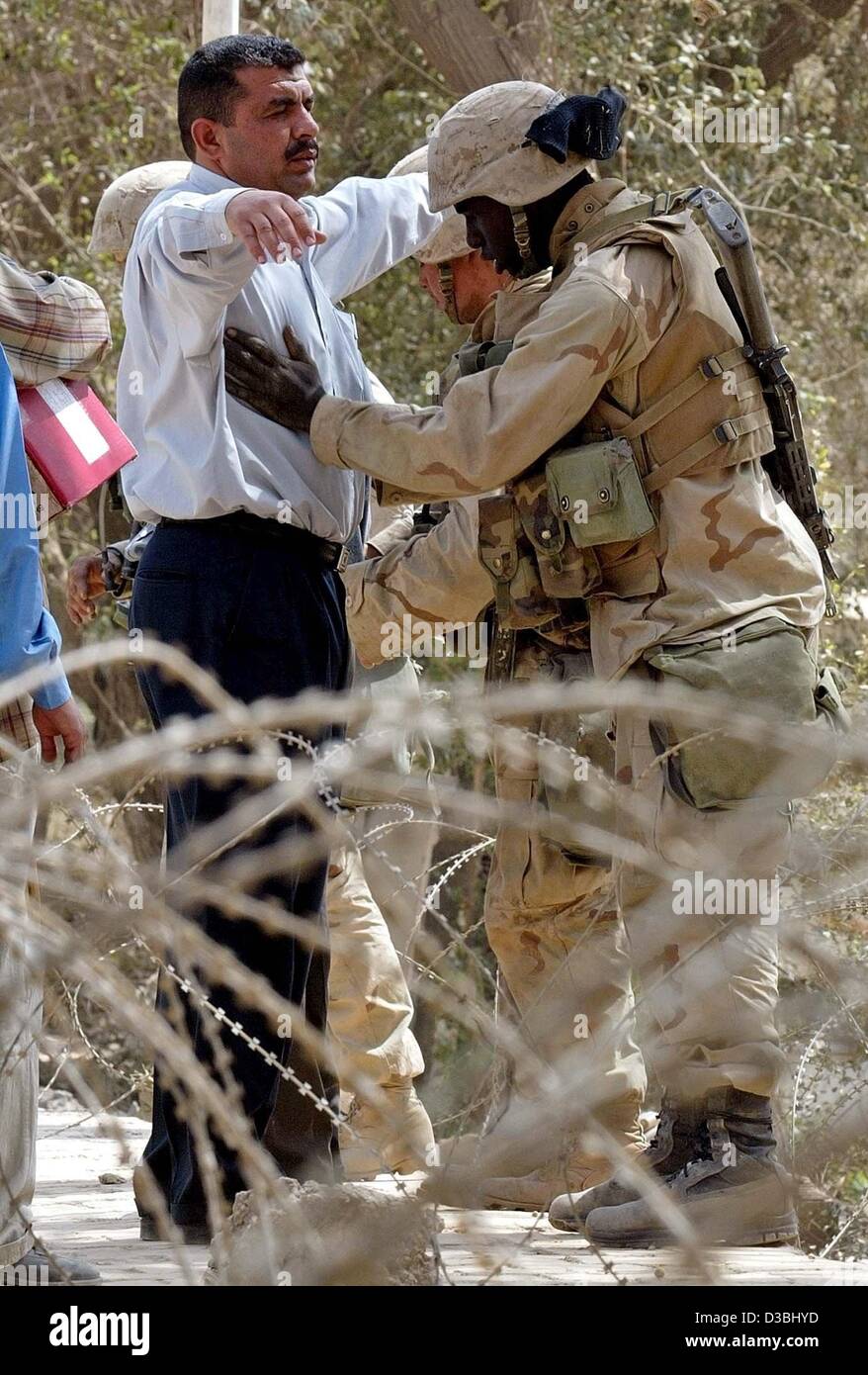 (Dpa) - Un US Army soldier cerca un uomo iracheno di fronte all'ingresso principale dell'Hotel Palestina a Bagdad, 15 aprile 2003. Alcuni 300 iracheni raccolte al di fuori dell'albergo, dove i marines americani hanno istituito un sistema di operazioni di base, per una terza giornata di protesta contro l'occupazione statunitense. La maggior parte dell'int Foto Stock