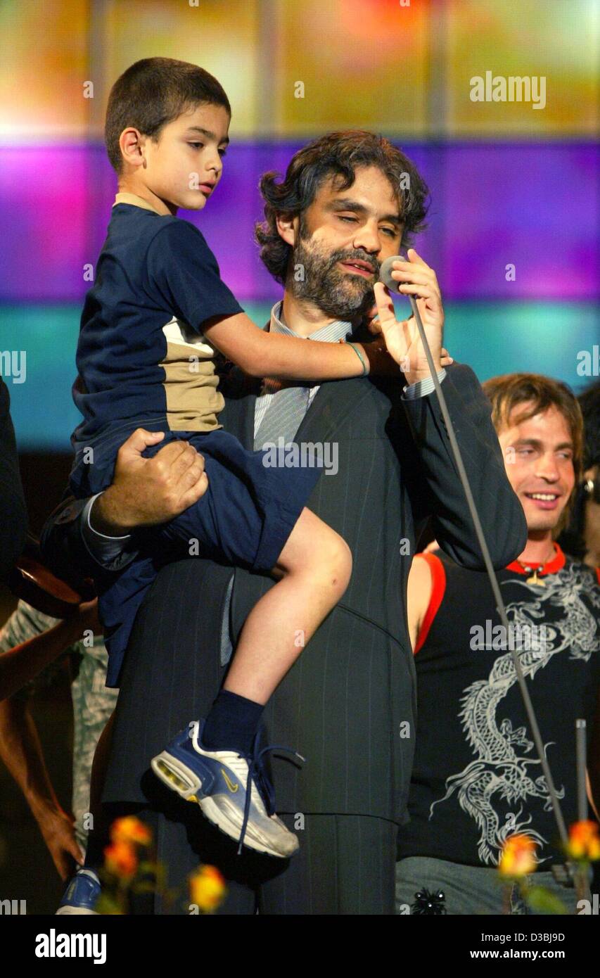 (Dpa) - Italian pop e la cantante lirica Andrea Bocelli tiene il suo Figlio sul suo braccio e canta durante una performance al "decima Pavarotti and Friends" Concerto di beneficenza a Modena, Italia, 27 maggio 2003. Foto Stock