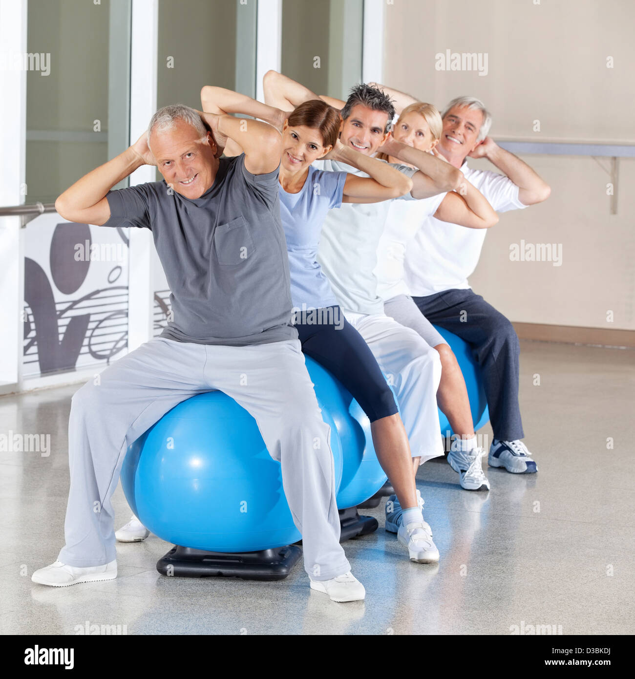 Felice dei cittadini anziani facendo esercizi per la schiena sulla palla nel centro fitness Foto Stock
