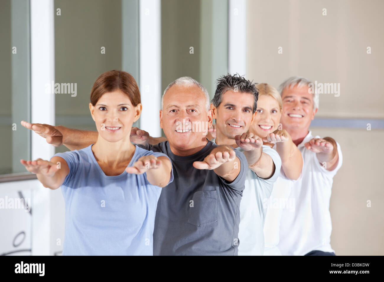 Gruppo di felice senior di persone facendo esercizi per la schiena in un centro fitness Foto Stock