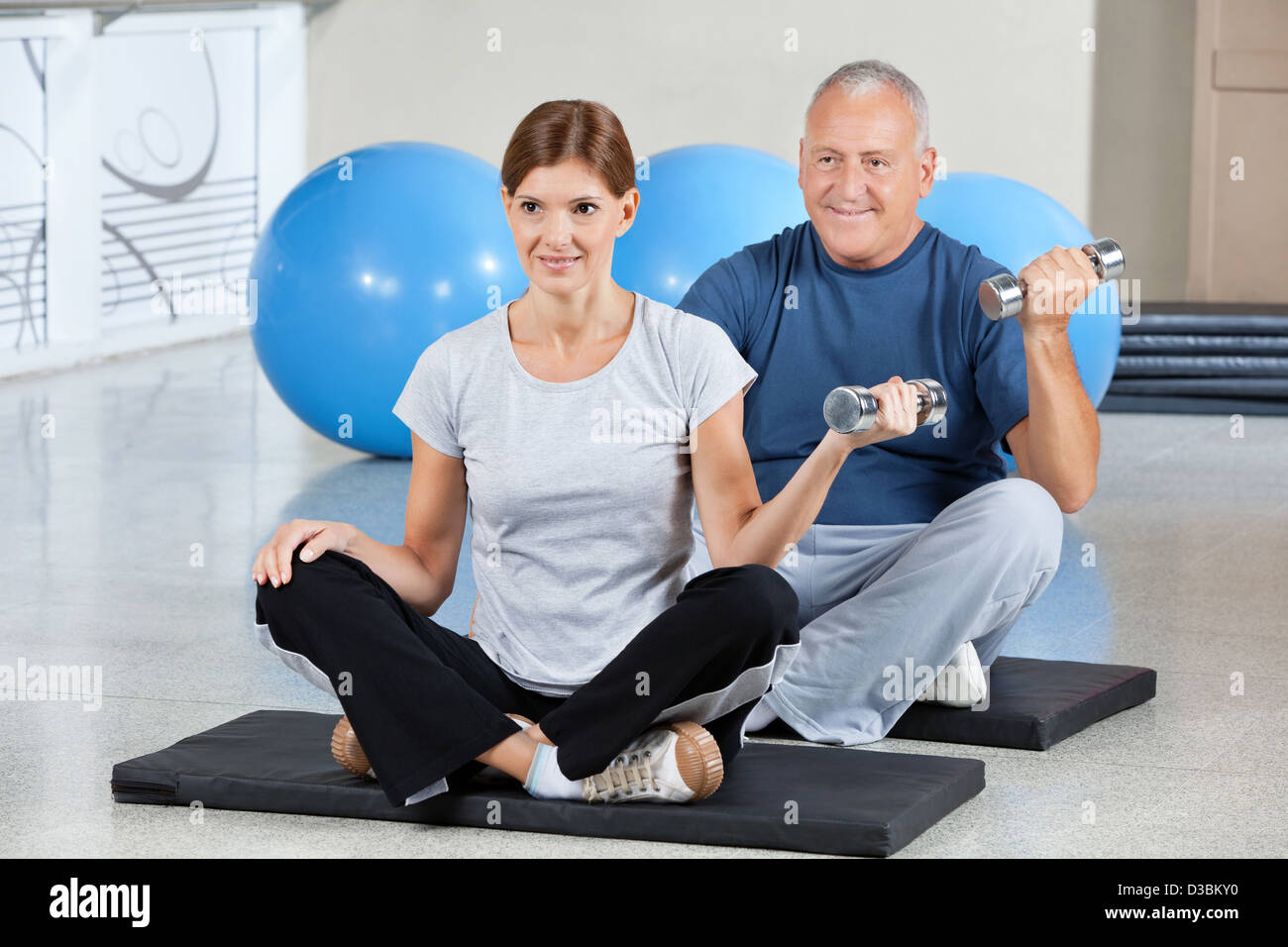 Uomo e donna della palestra stuoie utilizzando pesi nel centro fitness Foto Stock
