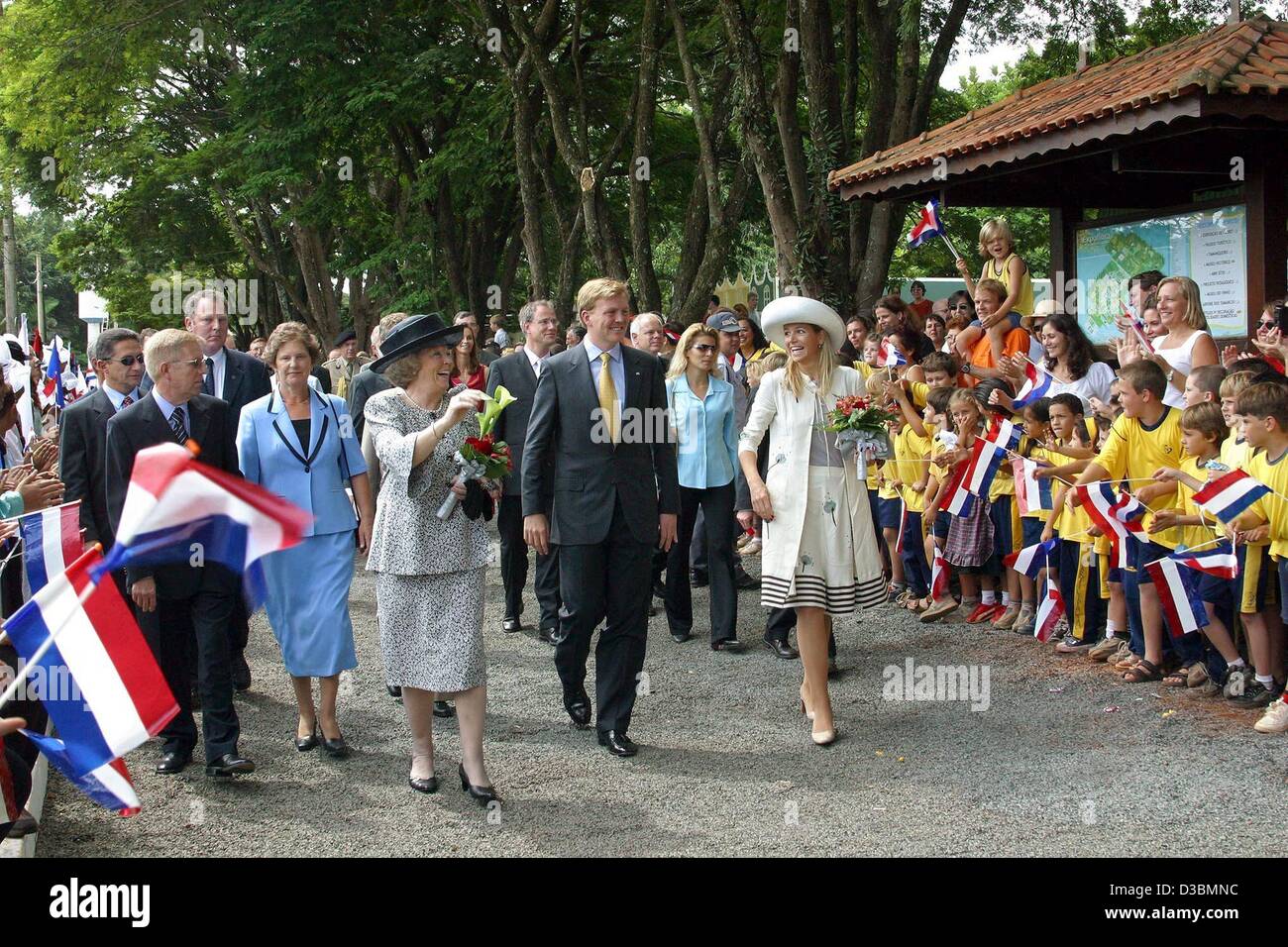 Regina olandese Beatrice (L), Crown Princess Maxima (R) e il principe ereditario Willem Alexander a piedi lungo una strada oltre un tifo, bandiera sventola folla per entrambi i lati durante la loro visita a una casa per i bambini affetti da HIV di età di 0 a 13 in Sao Paulo, Brasile, 27 marzo 2003. La regina olandese e la royal c Foto Stock