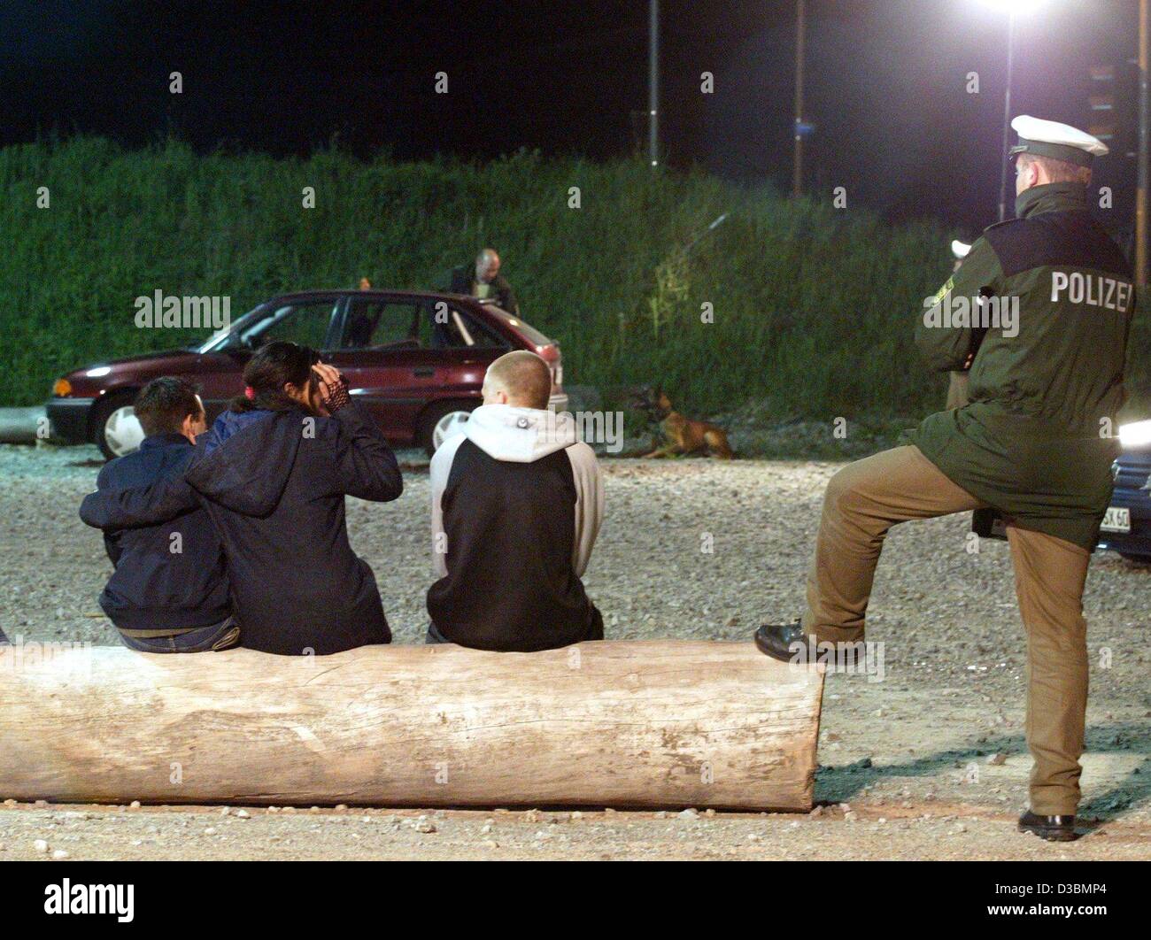 (Dpa) - un poliziotto sorge accanto ad un gruppo di adolescenti, mentre il suo collega controlla la loro auto con un farmaco tracking cane in Villingen-Schwenningen, Germania, 17 maggio 2003. Alcool e droghe controlli hanno aumentato ultimamente, perché un gran numero di incidenti in Germania sono causati da giovani visitatori discoteca Foto Stock