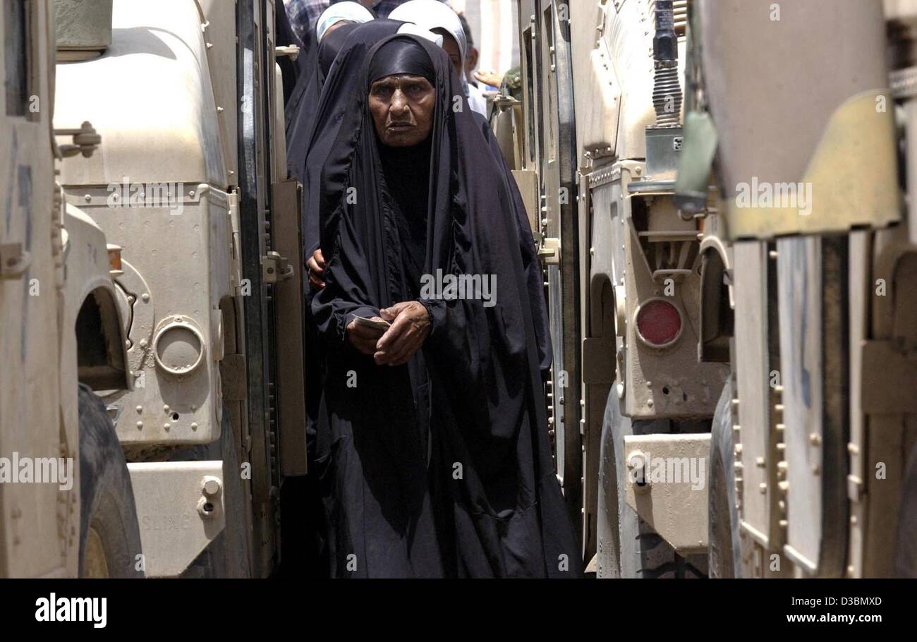 (Dpa) - Le donne irachene a piedi tra noi veicoli militari sul loro modo di ricevere un 40 US dollar emergency retribuzione dal ORHA (Organizzazione per il sollievo e aiuti umanitari) fuori ufficio pensioni a Bagdad, 21 maggio 2003. ORHA ha fornito 130 miliardi di dinari (circa 100 milioni di dollari USA) per pagare de Foto Stock