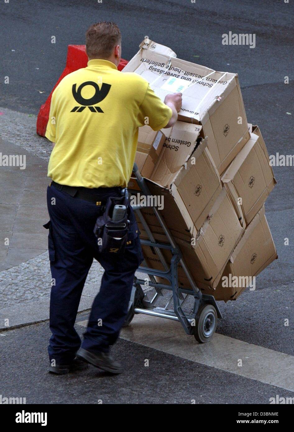 (Dpa) - un postino indossa una maglietta gialla con il logo della Deutsche Post in lingua tedesca (Post) sul retro e spinge un carrello caricato con pacchetti attraverso una strada nel centro di Berlino, 15 maggio 2003. Foto Stock