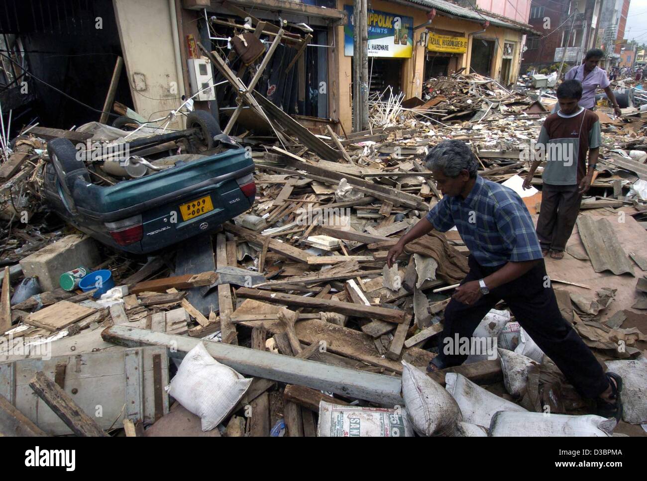 (Dpa) - Il popolo dello Sri Lanka ispezionare i detriti di case distrutte in Galle, Sri Lanka, 29 dicembre 2004. La costa dello Sri Lanka è stato uno dei settori più colpiti dal devastante tsunami che fino ad ora ha causato la morte di oltre 70.000 persone in Asia meridionale. Foto Stock
