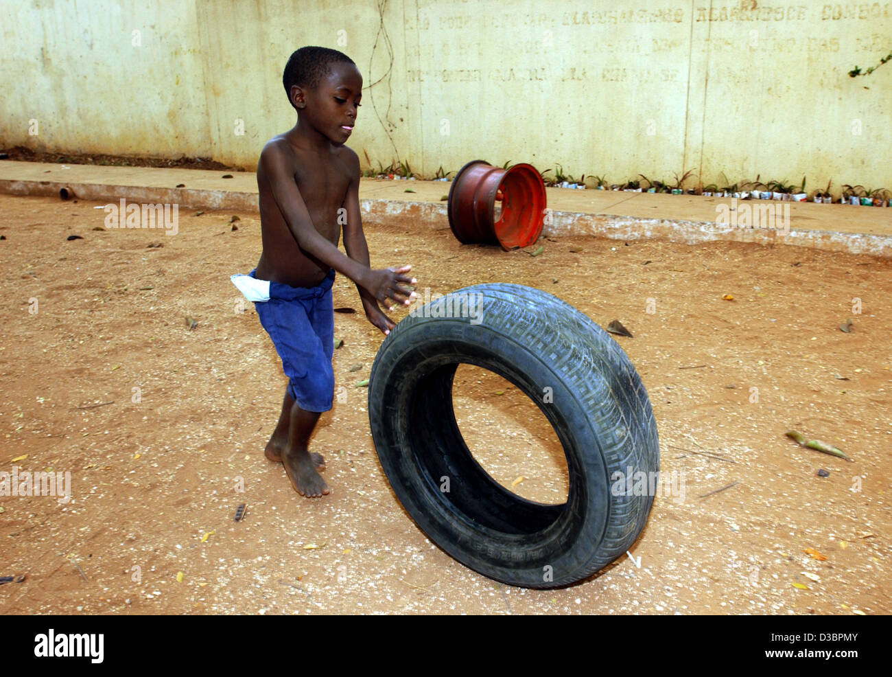 (Dpa file) - Otto-anno-vecchio Augusto gioca con un pneumatico al 'Centro Criancas Arnaldo Janssen', il centro per i bambini che vivono per le strade di padre Horacia, a Luanda, capitale dell Angola, 31 agosto 2003. Foto Stock