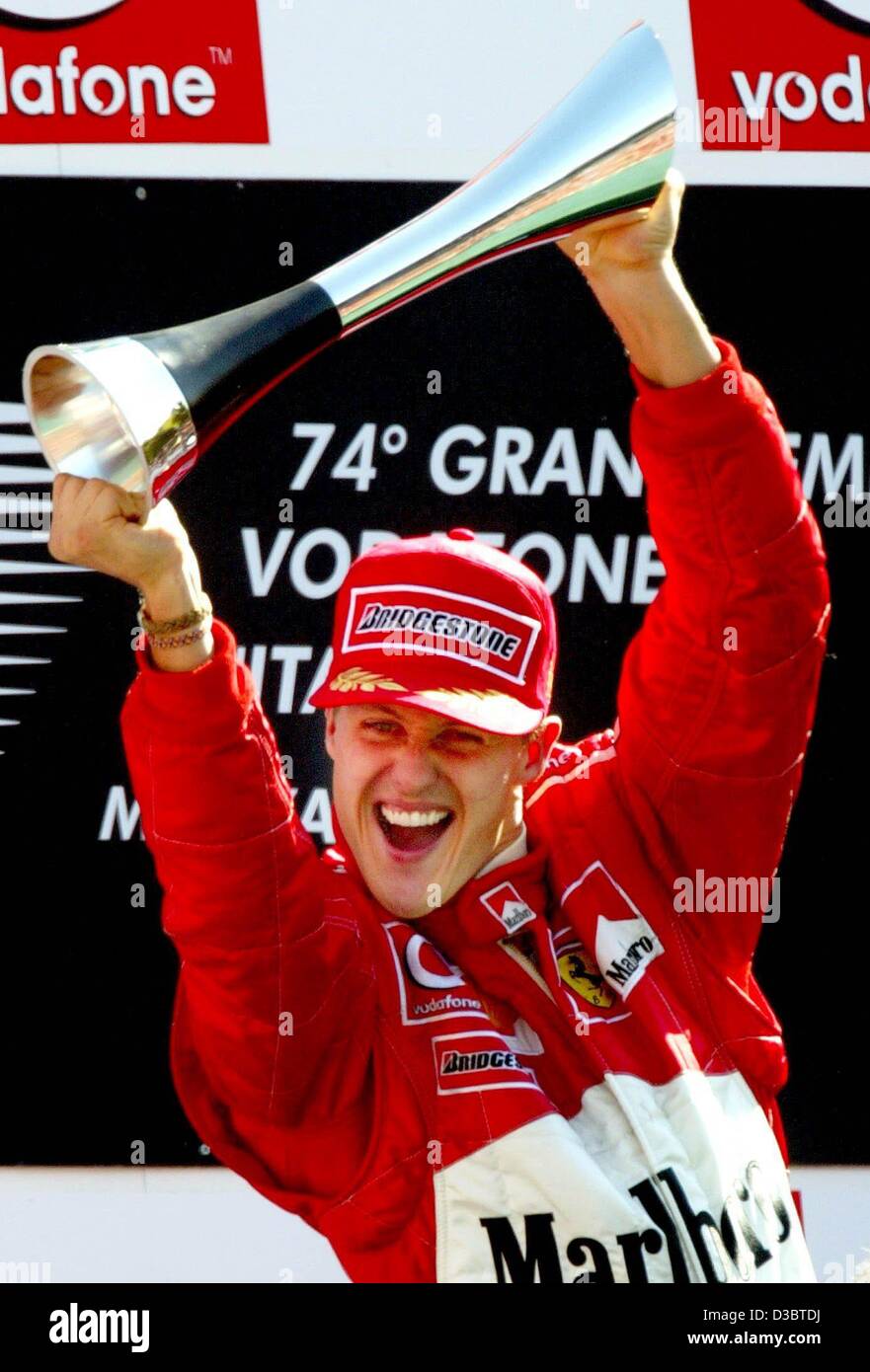 (Dpa) - Tedesco pilota di Formula Uno Michael Schumacher della Ferrari cheers onde e il suo trofeo dopo aver vinto il Gran Premio d'Italia a Monza, 14 settembre 2003. Schumacher porta ora in classifica generale con 82 punti. Foto Stock